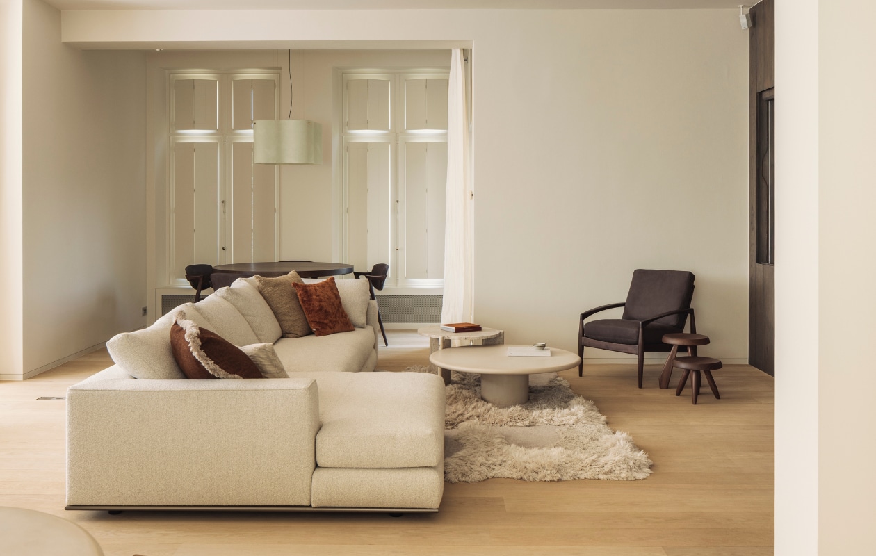 Stoelen en fauteuil Miyazaki Chair Factory, krukken Tabouret Berger van Cassina, greige mortex salontafel van Armand&amp;Francine, tapijt Cozy van Limited Edition, bank Minotti, kussens Rebo Home. Stijlvol Wonen 01-2025 | fotografie Stefanie De Neve (portret), Tijs Vervecken