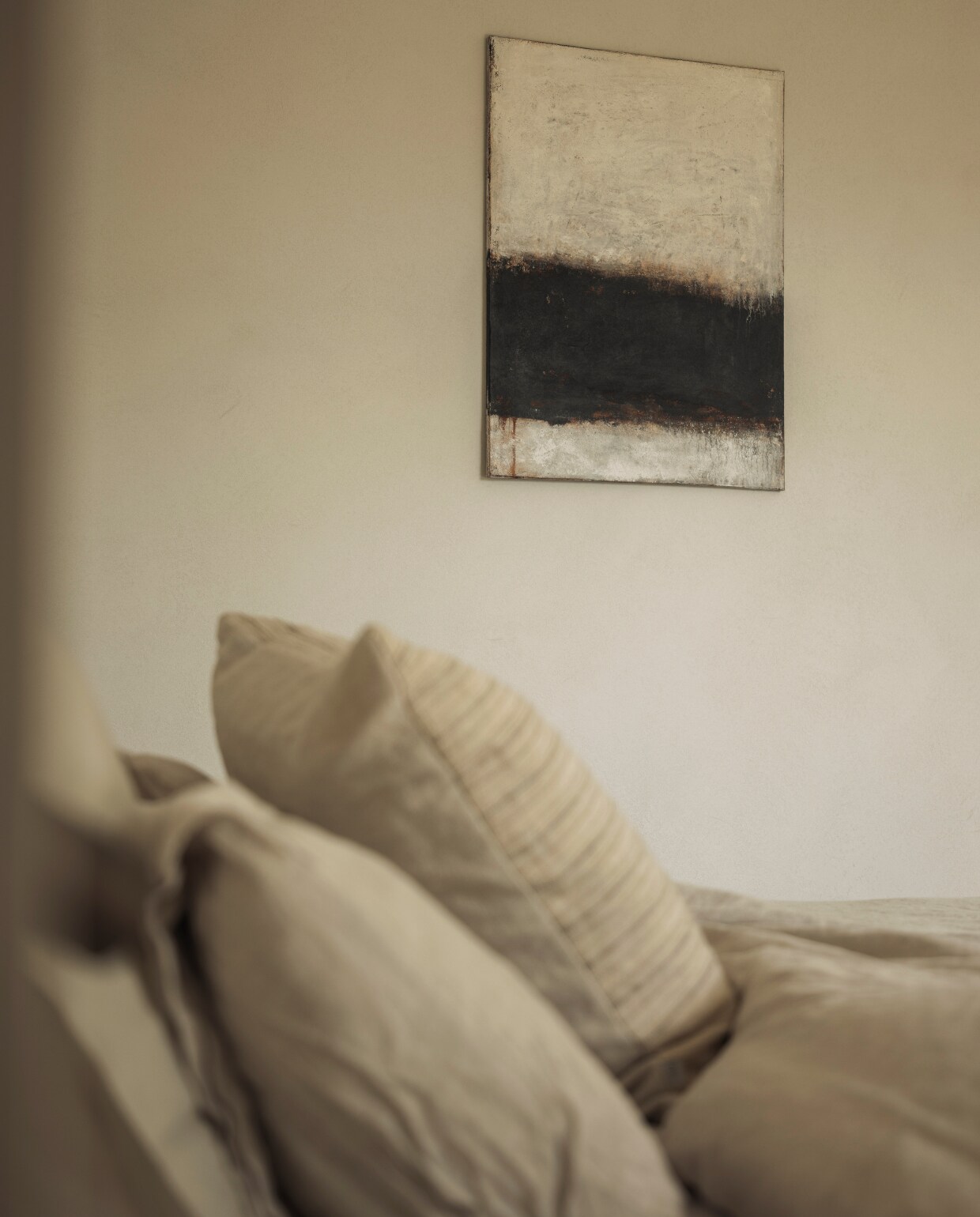Schilderij van Art Gaze by Astrid. De nachtkastjes van Zara Home kregen dezelfde kleur als de muur. Nachtlampje Trizo21, spots Prado. Stijlvol Wonen 01-2025 | fotografie Stefanie De Neve (portret), Tijs Vervecken