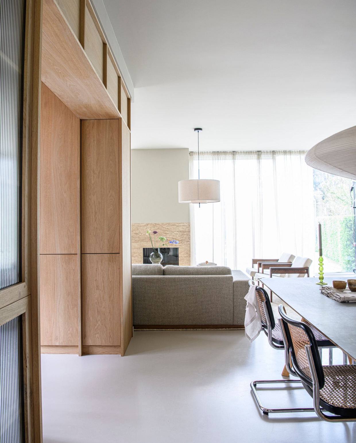 Gordijnen Aristide. Haard afgewerkt met travertin van SolidNature. Hanglamp Margin van New Works, vintage fauteuils Spectrum. vtwonen 01-2025 | styling Esther Loonstijn | fotografie Louis Lemaire