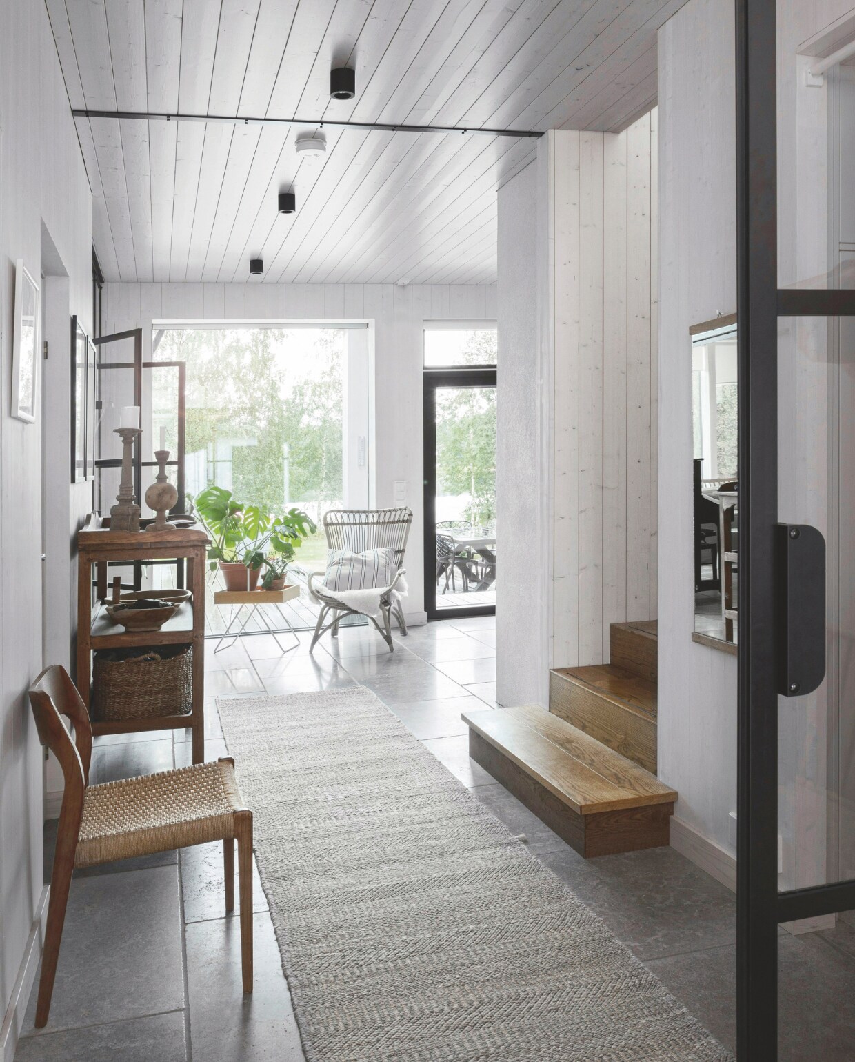 Stoel met zitting van Deens papierdraad van Niels Otto Møller. Rotanstoel van Sika-Design. Kalkstenen vloer in Burford Grey van Ekland Stone. Vloerkleed Dixie. vtwonen landelijk 01-2025 | styling &amp; fotografie Heikki Rautio