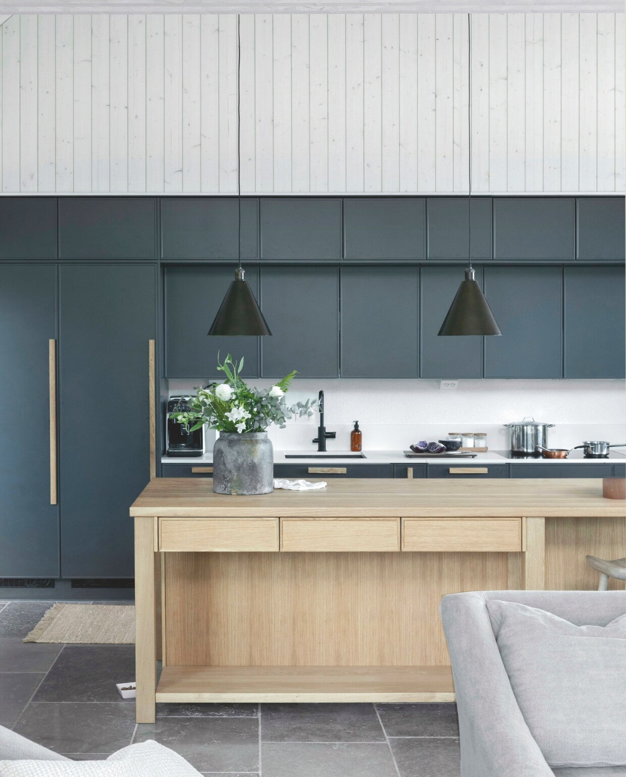 Eiken eiland en keuken ontworpen door Kirsi Luttinen, maatwerk van een plaatselijke timmerman. Inductie-kookplaat Siemens. Hanglampen Keats Conical Pendant van Neptune. vtwonen landelijk 01-2025 | styling &amp; fotografie Heikki Rautio