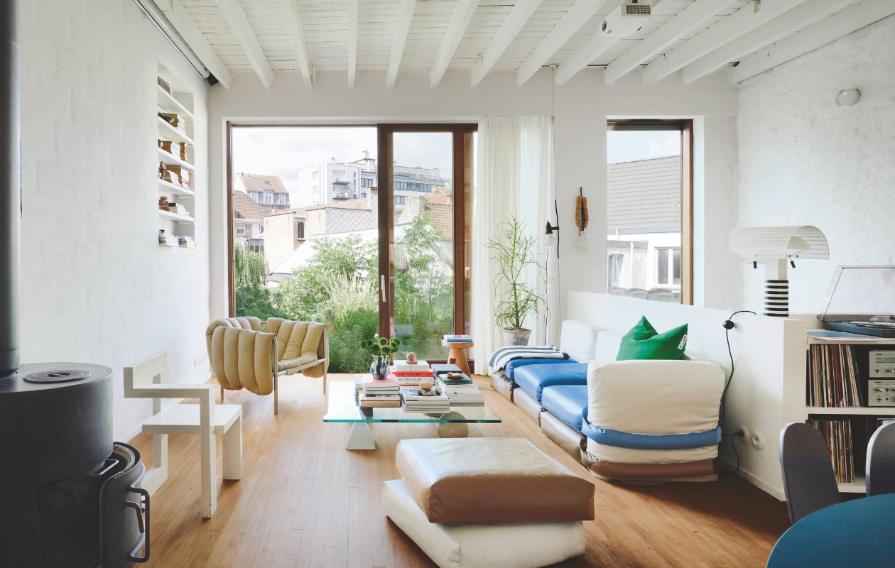 Als de temperatuur het toelaat, staat het grote schuifraam open. Het vormt een sterke verbinding met het groene dak. Steltman stoel van Rietveld en Puffy loungestoel van Faye Toogood voor Hem. Sofa van Muller Van Severen x Kassl Editions, Parentesi lamp van Flos, vintage salontafel Metaphora van Vignelli. In de muur zijn nissen gemaakt voor boeken en souvenirs. stijlvol wonen 02-2025 | productie Living Inside | fotografie Mr. Frank