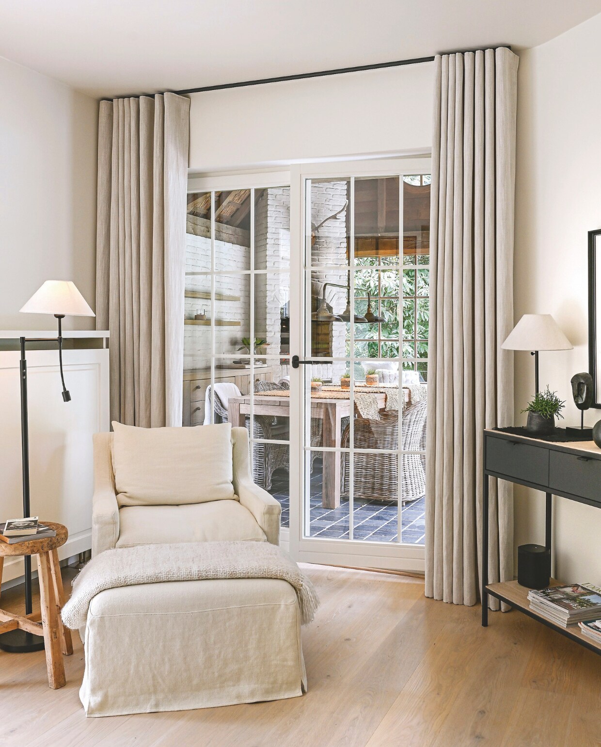 Fauteuil met hocker Les Campanules. Vergelijkbare staande lamp De Knotwilg Landelijk Wonen.Vergelijkbare bijzettafel Wen Natural Living.Sidetable Op maat gemaakt door Interno Interieur. Schemerlamp Deba Meubelen. Gordijnstof Bilbao. Massief eiken parket behandeld door Ronald Roels. Muurverf eigen mengsel van 75% witte verf en 25% FL104 Flamant. vtwonen Landelijk 2-2025 | Fotografie Claude Smekens | Tekst Yvonne van Galen