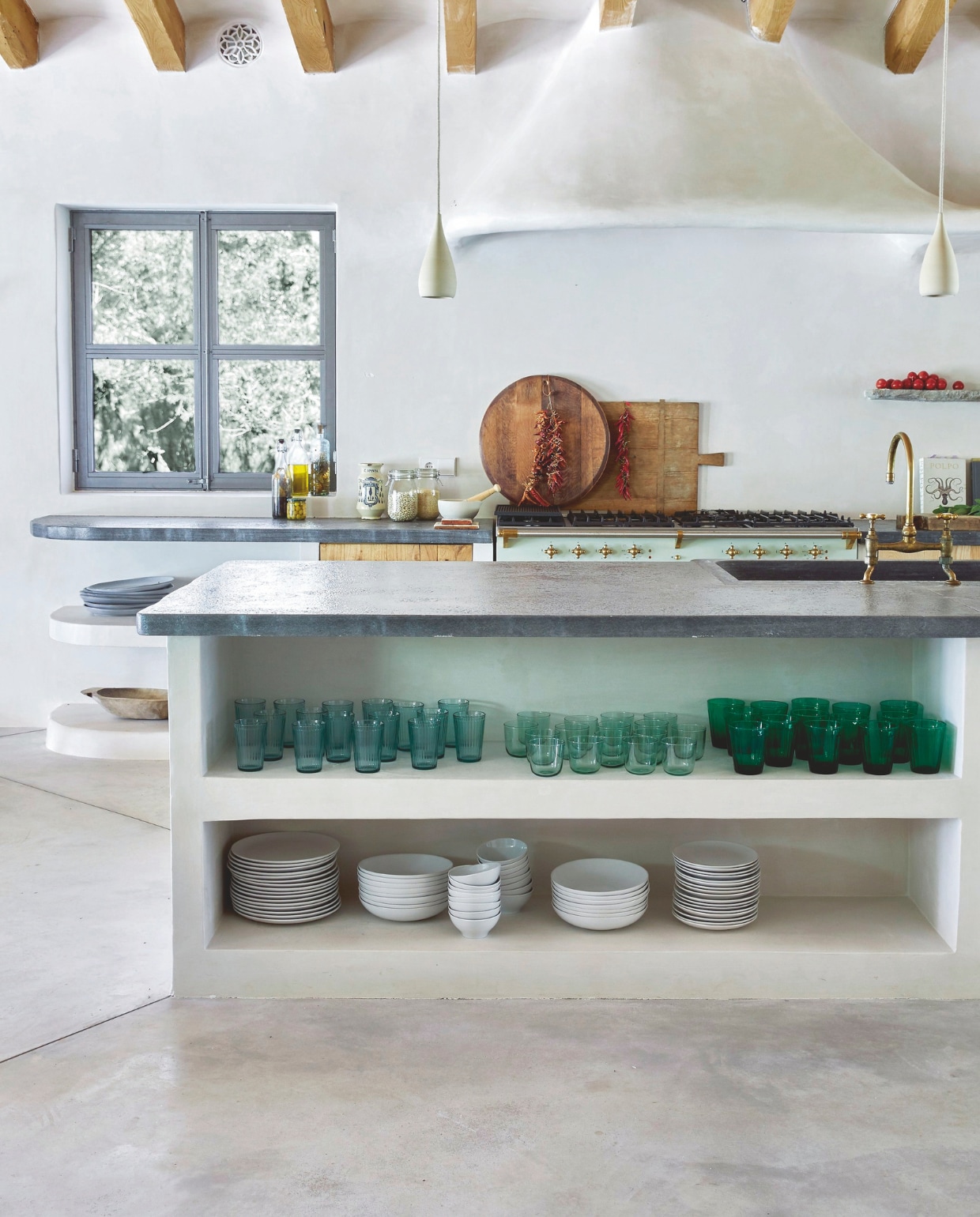 Blikvanger in de keuken: de met kalkpleister afgewerkte gewelfde afzuigkap naar ontwerp van More Design. Glazen Gordiola. Snijplanken uit nabijgelegen stad Sóller, soortgelijke via Oldenhof. Fornuis Lacanche. Kranen BarberWilsons &amp; Co. vtwonen 02-2025 | Styling Tille Del Negro | Fotografie Greg Cox | Tekstbewerking Wilma Tjalsma-Smits