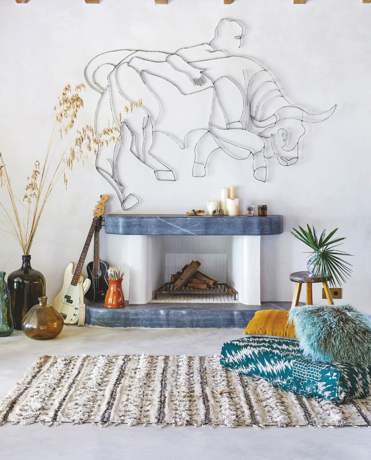 Nieuw gebouwde open haard, afgewerkt met kwartsiet, dat ook werd gebruikt voor het aanrecht. Kunstwerk uit de collectie van Paul. Traditionele Mallorcaanse opslagflessen voor wijn en olijfolie van lokale vlooienmarkt. Wollen Berbertapijt tijdens vakantie meegenomen uit Marrakech. vtwonen 02-2025 | Styling Tille Del Negro | Fotografie Greg Cox | Tekstbewerking Wilma Tjalsma-Smits