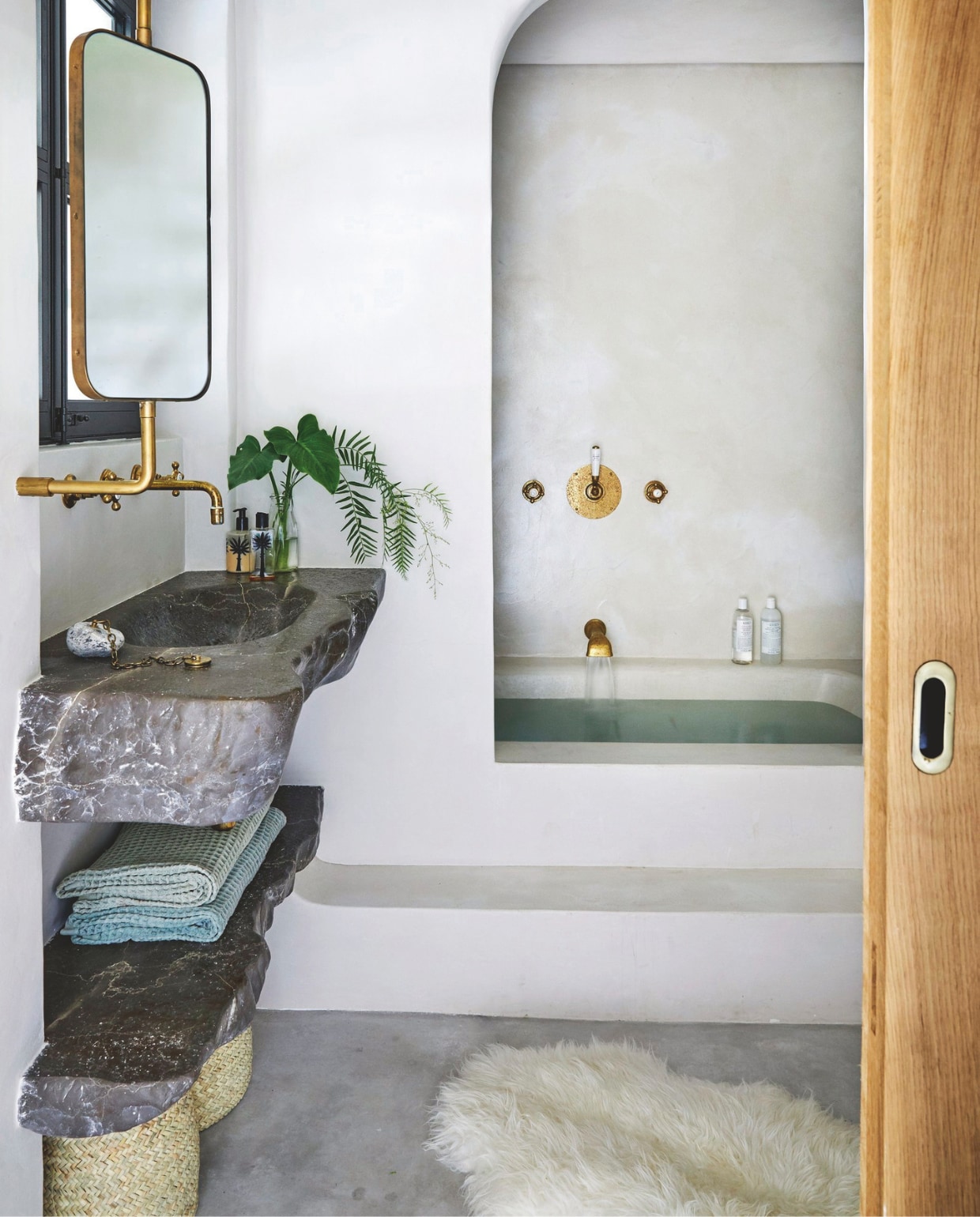 En-suitebadkamer op maat gemaakt, ontworpen door More Design, inclusief hetgietijzeren bad, afgewerkt metmicrocement, de wastafel en plank van kwartsiet en de draaibaremessing spiegel Soortgelijke vacht Ikea. vtwonen 02-2025 | Styling Tille Del Negro | Fotografie Greg Cox | Tekstbewerking Wilma Tjalsma-Smits