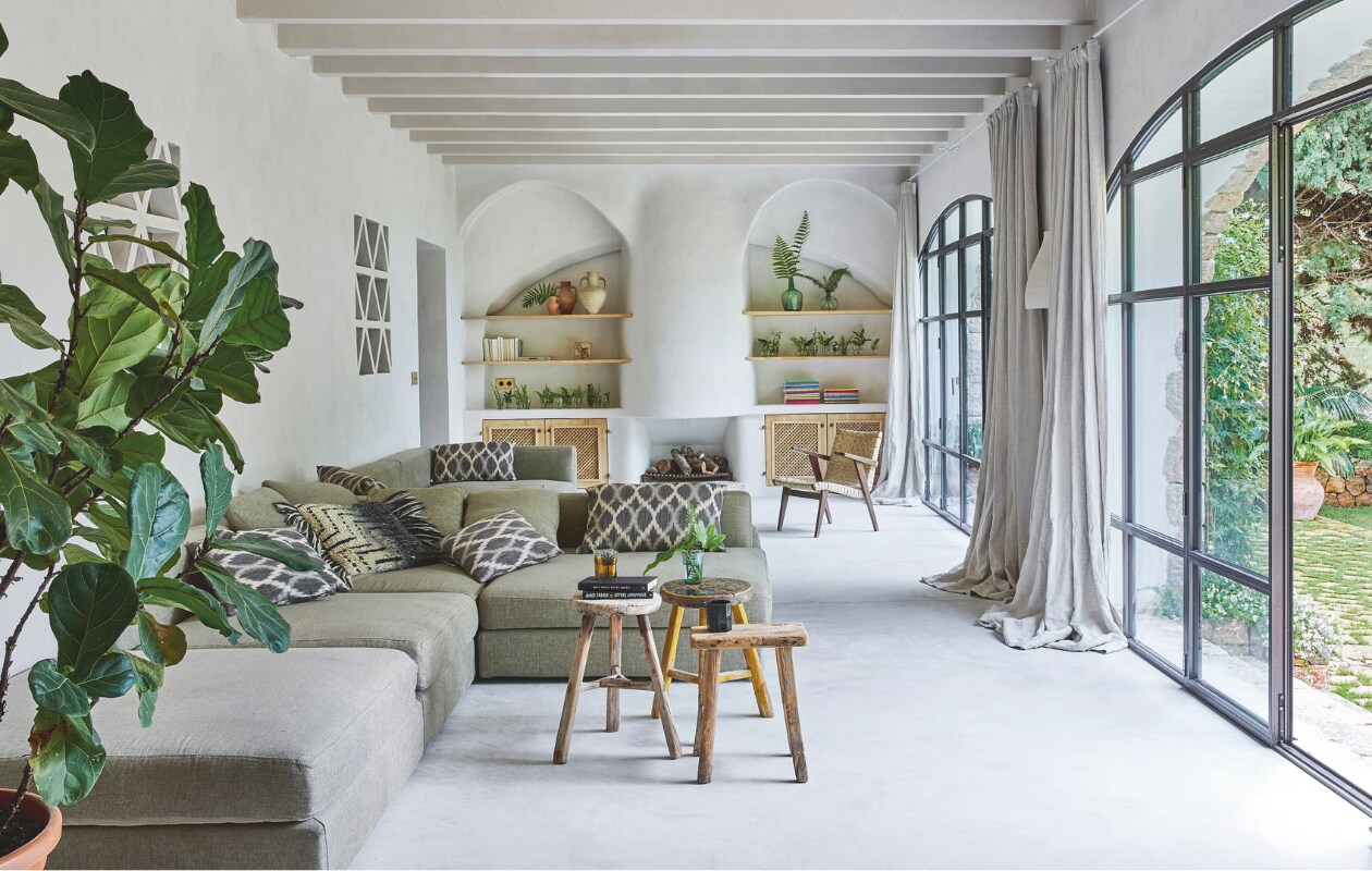 De banken in de woonkamer hadden de eigenaren al. Ze zijn opnieuw bekleed met zacht linnen. Kussens met een soort-gelijke vintage, mediterrane uitstraling zijn te koop bij Loods 5. Een aantal krukjes in huis kwamen uit het originele huis. Andere kleine meubels en accessoires zijn door de bewoners gekocht op de vlooienmarkt in Consell. De betonnen balken in de woonkamer zijn net als het plafond en de muren afgewerkt met kalkverf, voor een aaibare uitstraling. vtwonen 02-2025 | Styling Tille Del Negro | Fotografie Greg Cox | Tekstbewerking Wilma Tjalsma-Smits