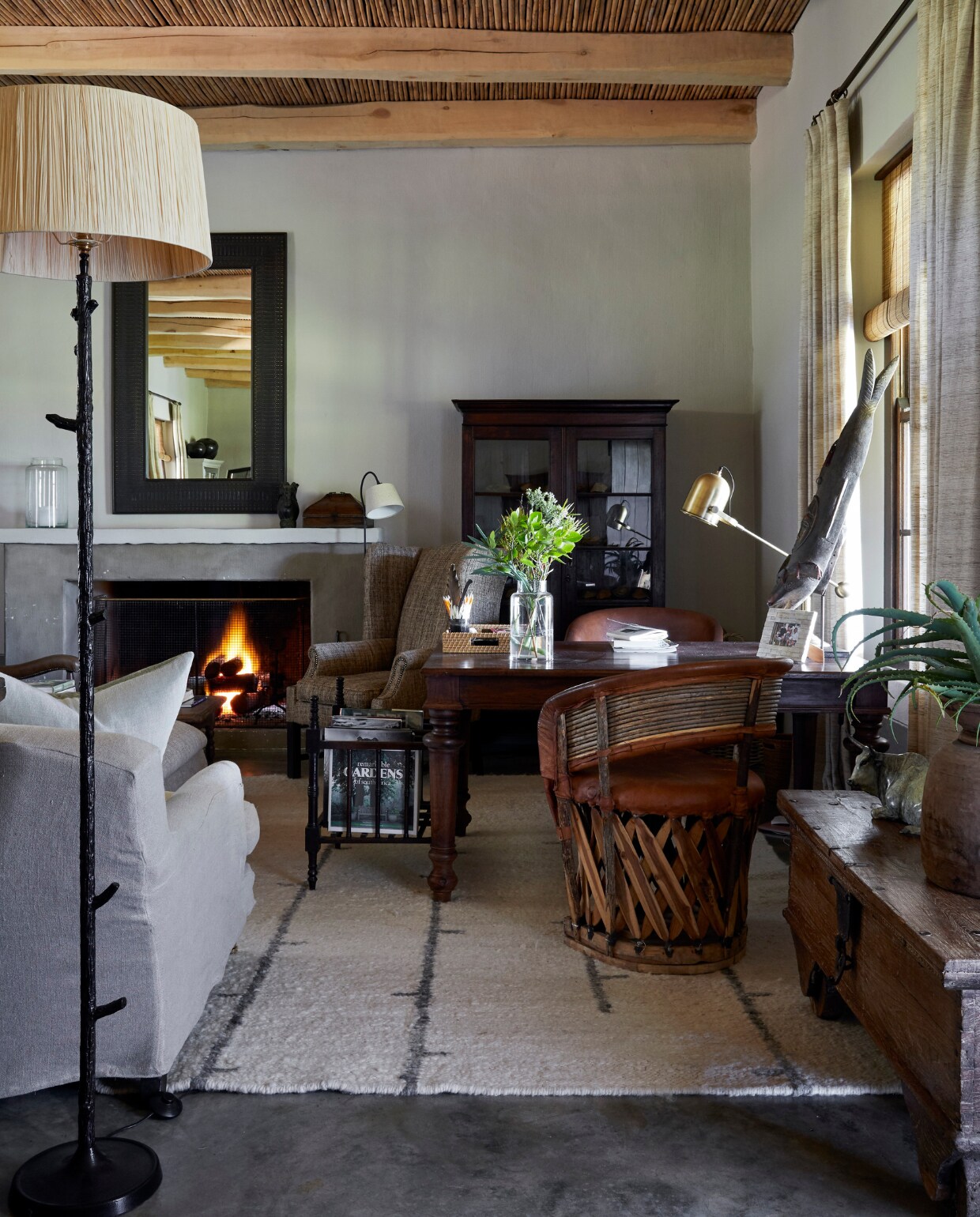 Een interessante Mexicaanse stoel van hout en leer staat naast een bureau in de woonkamer. Beide vintage. Omdat de eigenaar over de hele wereld heeft gevist, is de Ethiopische walvissculptuur op het bureau hem zeer dierbaar. vtwonen landelijk 02-2025 | Styling Luanne Toms | Fotografie Elsa Young | Tekstbewerking Mirjam Rosema-Verhulst