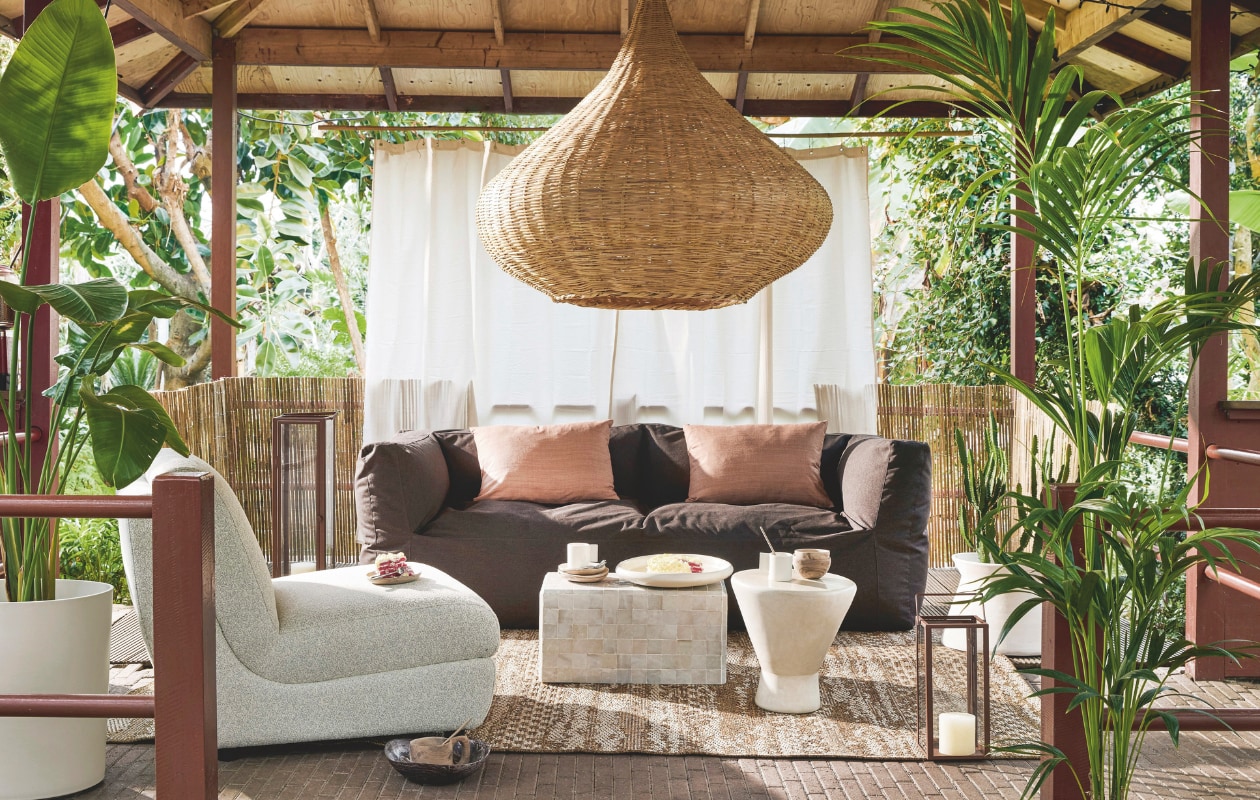 Driezits loungebank New Brown, Sunbrella-stof, 223x80x75 cm (bxdxh)€ 1595,- (bryck.nl). Outdoor fauteuil Mississippi van Zuiver, olefin en polyester, 82x100x83 cm (bxdxh) € 1140,-, polypropyleen buitenkleed Jute Oos van Vloerkledenloods, 200x290 cm € 199,-, kunststof plantenbak Eden Aquacare High van Elho € 139,-, kussens Almond van Urban Nature Culture, zijde en katoen, 60x40 cm, per stuk € 69,95, walnoothouten mok met oor van Household Hardware, groot € 49,50, bijzettafel Kubus van Household Hardware, beton en zellige tegels, 30x30x60 cm (lxbxh) € 499,-, tadelakt bijzettafel TamTam van Household Hardware, 40x47 cm (Øxh)€ 345,-, strooien lampenkap Drop van Household Hardware, 120x40 cm (Øxh) € 319,-, tadelakt schaal van Household Hardware, 38 cm (Ø) € 69,-, keramieken mok met vierkant oor van Household Hardware € 19,95, cortenstalen windlicht Celso L van Urban Nature Culture, 21x21x80 cm (lxbxh) € 119,-, cortenstalen windlicht Celso S van Urban Nature Culture, 21x21x80 cm (lxbxh) € 79,95 (shop.vtwonen.nl). Mousselinen douchegordijn € 19,95 (hm.com). Gespleten bamboe balkonscherm, 300x90 cm (bxh)€ 30,99 (karwei.nl). vtwonen 03-2025 | styling kelly van gendt | fotografie peggy janssen