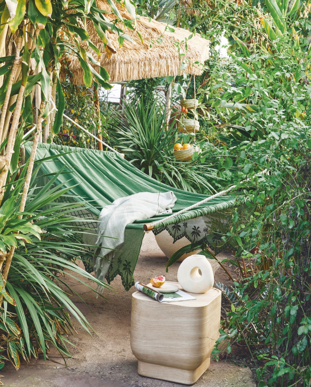 Katoenen hangmat Olive, 115x210 cm (bxl) € 499,-, parasol Patio, raffia en aluminium, 300 cm (Ø) € 499,- (hkliving.com). Plaid, acryl, polyester en wol € 29,99 (hm.com). Keramieken vaas Spada Sand van Urban Nature Culture € 49,95, walnoothouten bord van Household Hardware € 14,99, zeegras etagère Essaouira, 70 cm (h) € 45,-, betonnen bijzettafel Noble van Zuiver, 45x45x47 cm (bxdxh)€ 469,- (shop.vtwonen.nl) vtwonen 03-2025 | styling kelly van gendt | fotografie peggy janssen