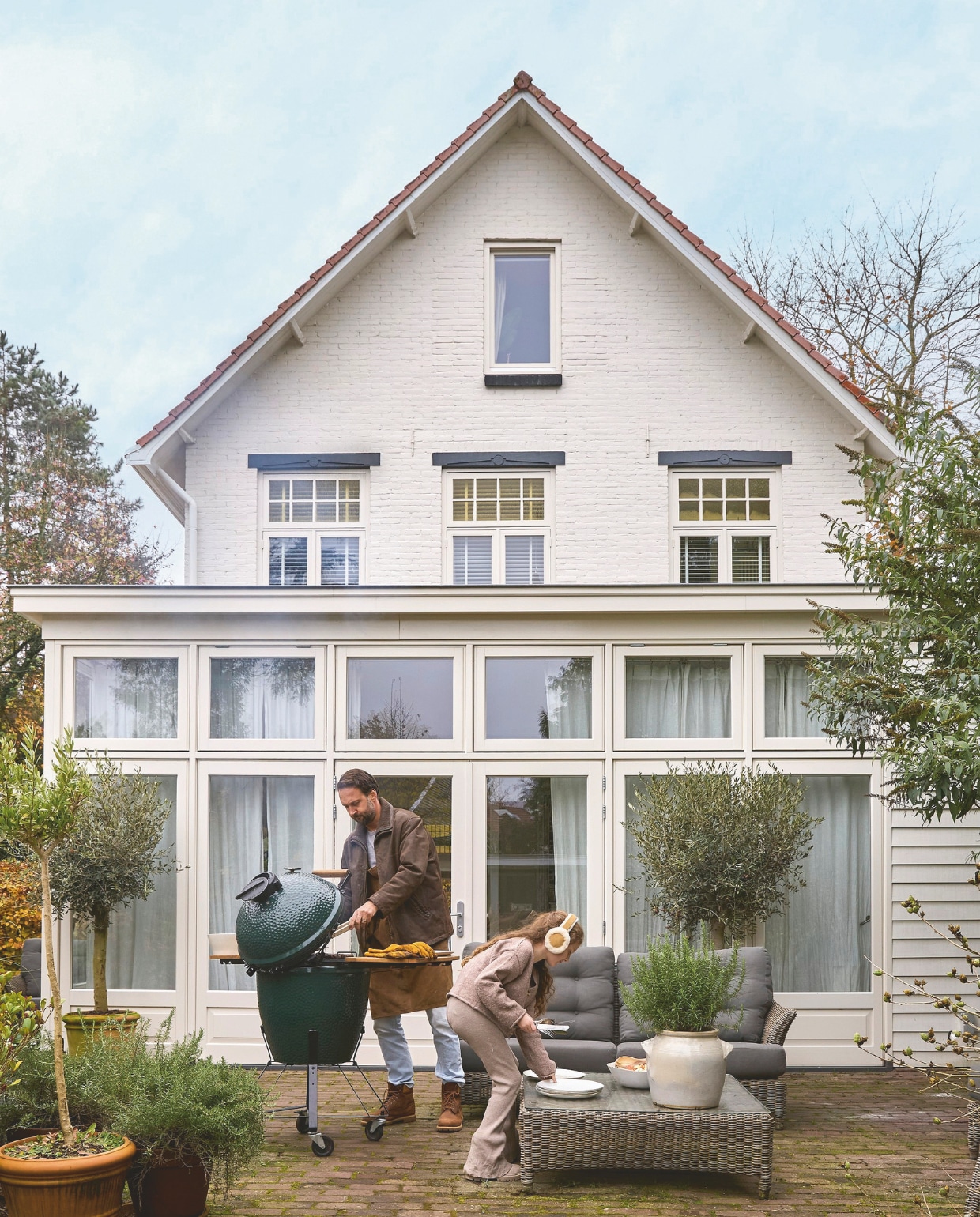 Wouter en dochter Annabelle in de achtertuin. Tuinset  Valentine van 4 Seasons Outdoor. Barbecue Big Green Egg. Olijfbomen en potten Kwekerij Groeneveld en De Bosrand Brocante. Verfkleur huis Ral 9001. vtwonen Landelijk 02-2025 | Styling Marianne Luning | Fotografie Tjitske van Leeuwen | Tekst Renate Wilms