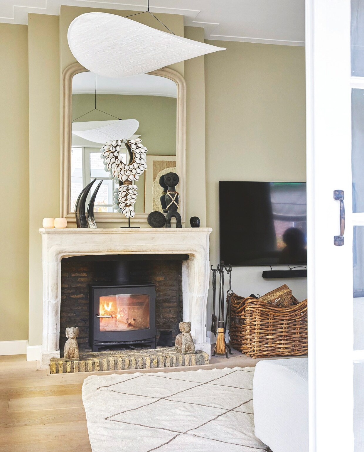 Houtkachel Ivar van Dik Geurts. Antieke zandstenen schouw van handelaar in oude bouwmaterialen. Houtmand ’t Achterhuis, Spiegel Lifestyle. Lamp Tense van New Works. vtwonen Landelijk 02-2025 | Styling Marianne Luning | Fotografie Tjitske van Leeuwen | Tekst Renate Wilms
