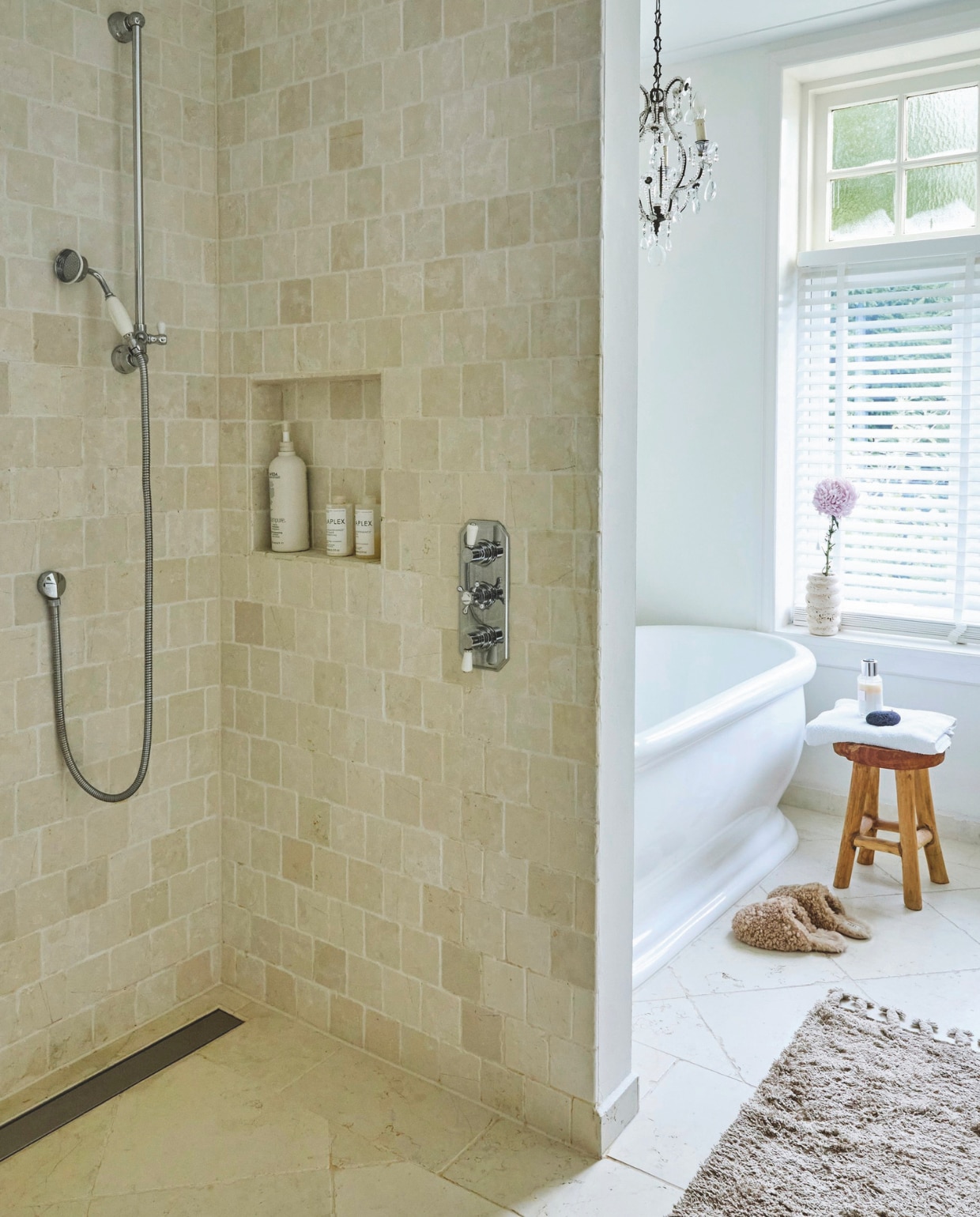 Bad van Heritage via Windsor Bathrooms. Natuurstenen wand- en vloertegels van Meisjes van Steen. Kruk kringloopvondst. De kroonluchter is een erfstuk. Sloffen Ugg. vtwonen Landelijk 02-2025 | Styling Marianne Luning | Fotografie Tjitske van Leeuwen | Tekst Renate Wilms
