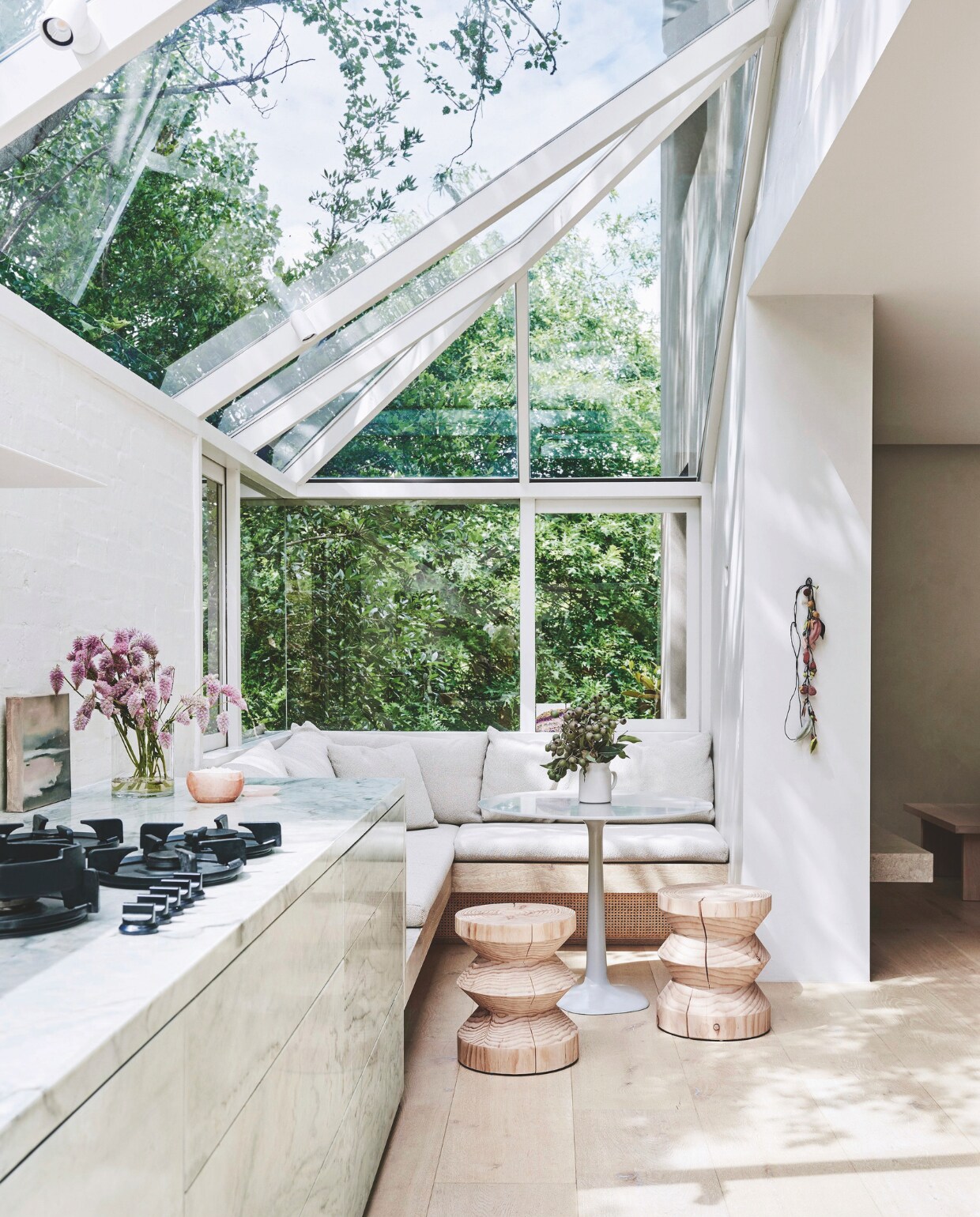 In de keuken creëerde Susi een relaxte plek om te ontbijten. Bank met stoere linnen kussens op maat gemaakt. Krukken van Mark Tuckey. Marmeren tafel van Paul Barbera. Het serredak speelt met geometrische vormen. vtwonen stijlvol 03-2025 | fotografie Lisa Cohen | tekst Tanne Donjacour Gielen | productie Living agency