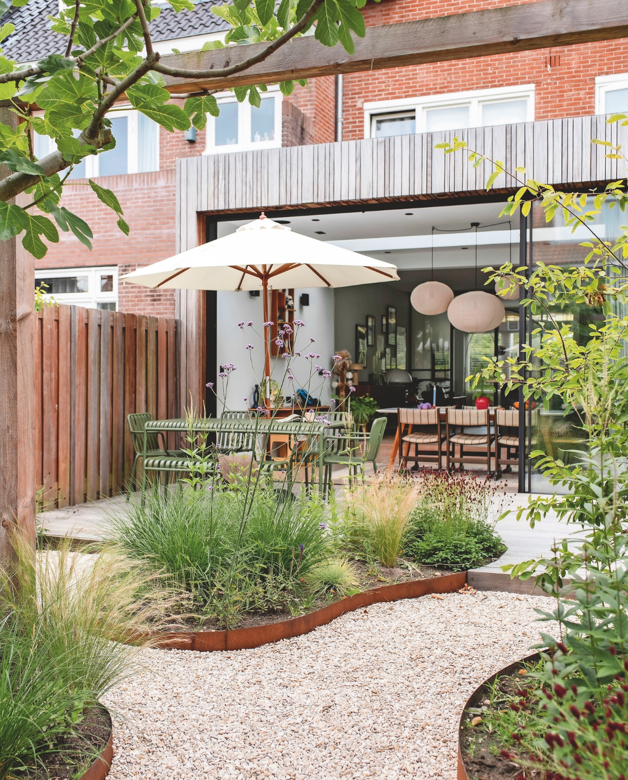 Eettafel en -stoelen Hay. Parasol Skagerak. Tuin ontworpen door Studio Eik Tuinontwerp, aangelegd door Schaffelaar Hoveniers. vtwonen 03-2025 | fotografie studio keeelly | tekst caroline westdijk