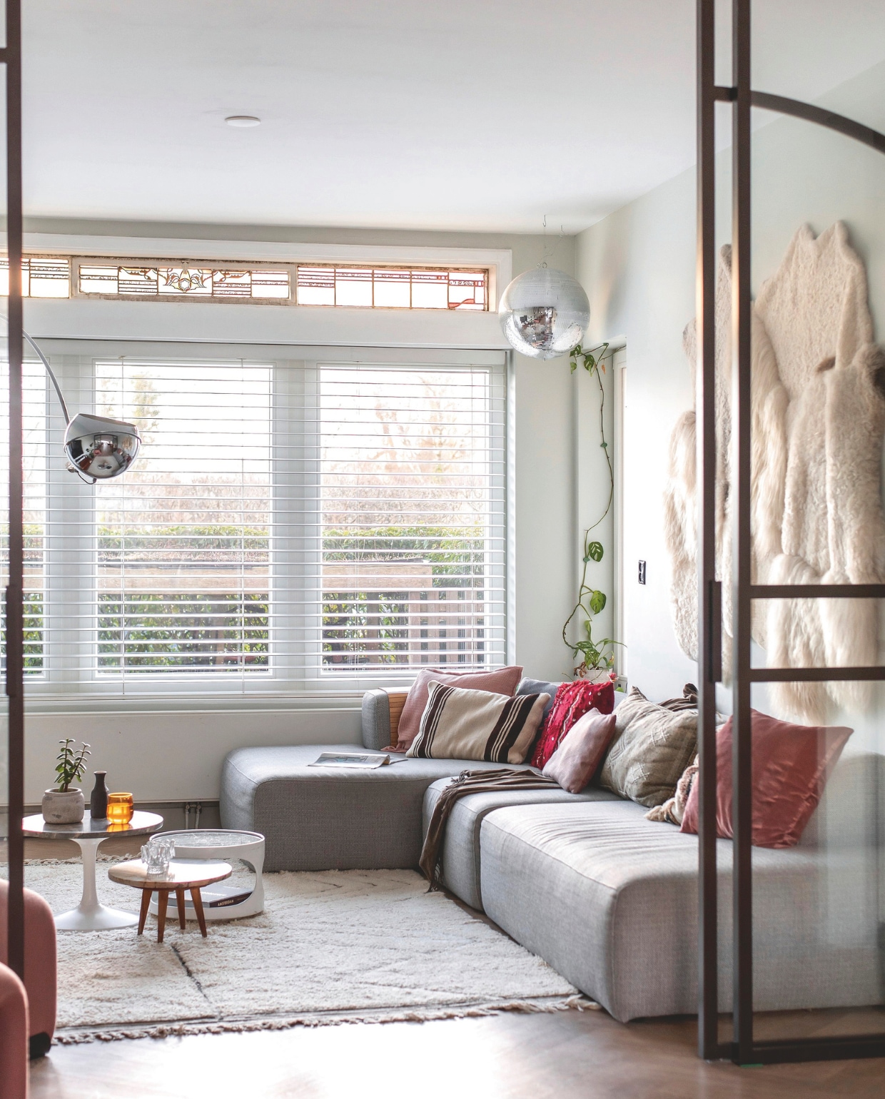 Bank X6 van 4x6 sofa. Kussens Karwei, Ikea, Hema en Stoov.  Vintage tafel met witte poot en houten bijzettafel Sip&amp;Clara Pop-up Store. Witte bijzettafel met ronde opening en vaas vintage. Glas Sissy-Boy Homeland. Vloerkleed Living Maroc. Zilveren bollamp uit ouderlijk huis Jessica. Stalen schuifdeuren Stuimer Metalworks. Schapenvachtenkleed Van Buren Bolsward. vtwonen 03-2025 | fotografie studio keeelly | tekst caroline westdijk