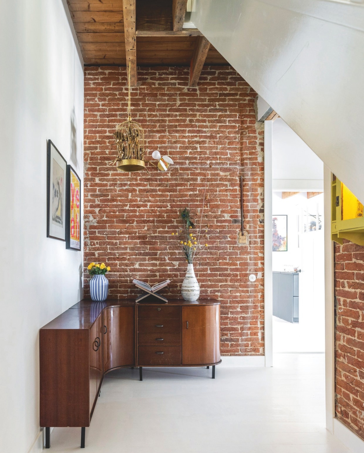 Dressoir Marktplaats. Gestreepte vaas Hay. Boekenstandaard Nort. Wandlamp Lucellino van Ingo Maurer. Gouden kooi kunstproject. Kunst aan muur Rien Poortvliet. Zeefdruk Gumbootz. Kast aan muur erfstuk. vtwonen 03-2025 | fotografie Margriet Hoekstra