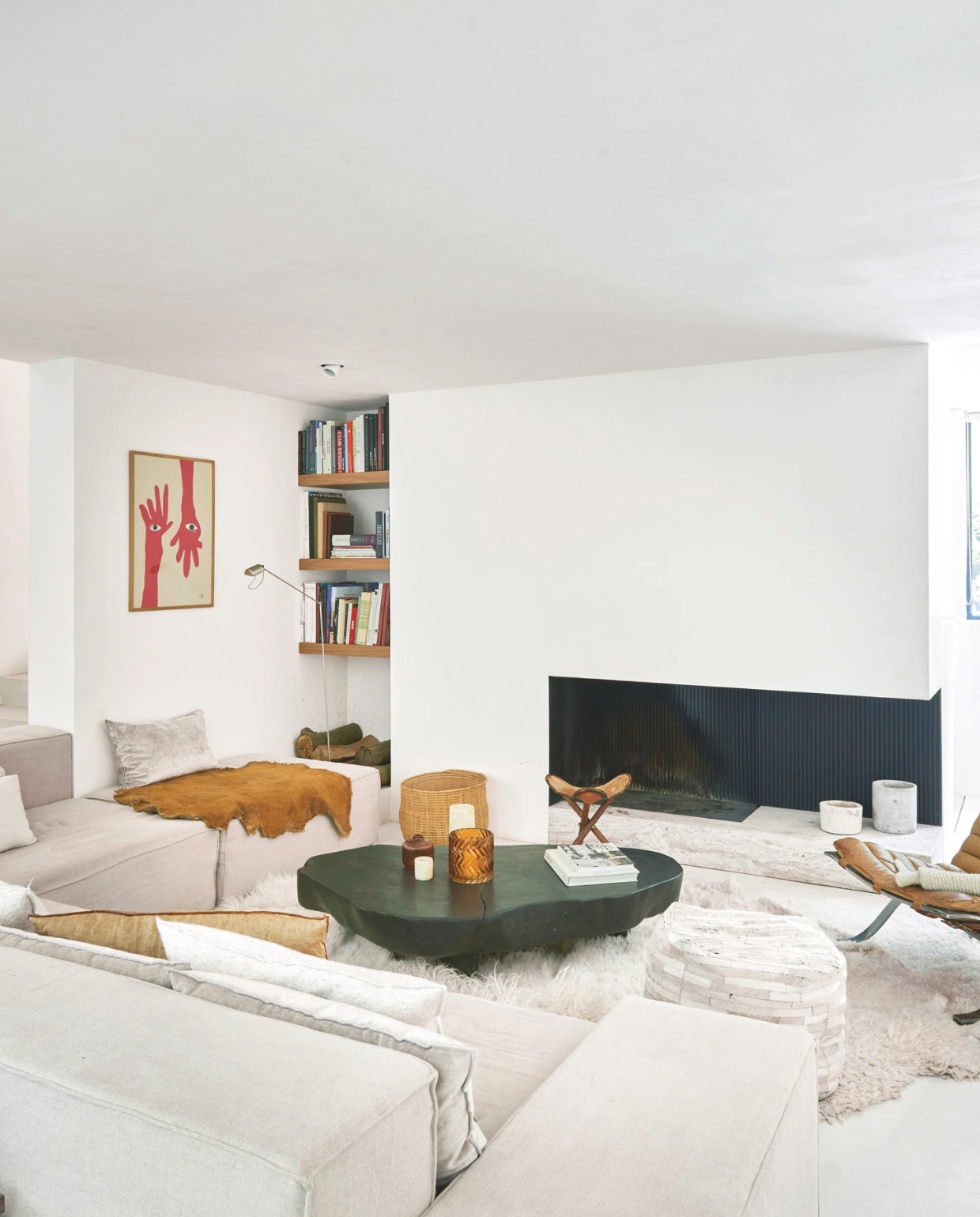 De woonkamer is ingericht is met zachte materialen als leer, textiel en wol. Bank op maat gemaakt en ontwerpen door Catleen. Salontafel Mombaers. Poef vintage. Houten kruk Swapp. Leeslamp Lumina. Vloerkleed Carine Boxy, stoel Ari van Arne Norell. Kunstwerk Anna Mörner. vtwonen stijlvol 03-2025 | Fotografie Mr. Frank |Tekst Tanne Donjacour Gielen