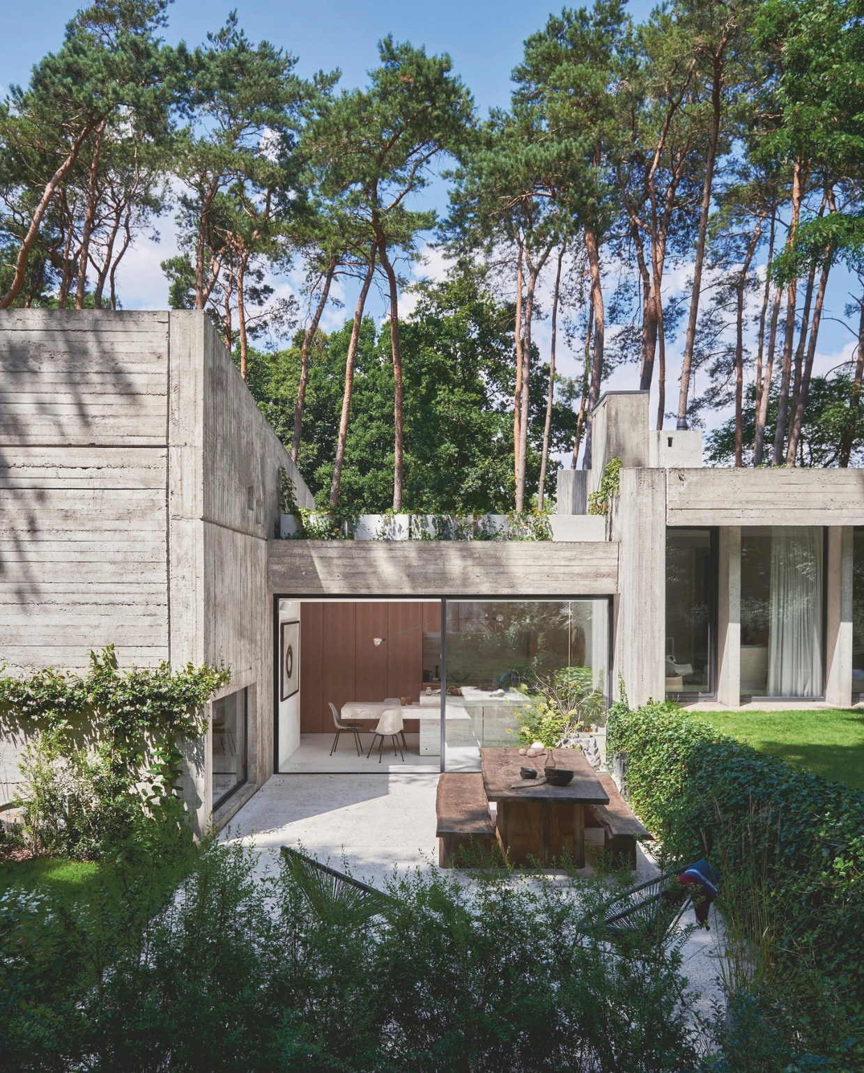 De architect van de villa, Marc Corbiau, heeft ook de tuin en het terras ontworpen. Zwarte Acapulco chairs. Houten tafel en banken op maat gemaakt. vtwonen stijlvol 03-2025 | Fotografie Mr. Frank |Tekst Tanne Donjacour Gielen