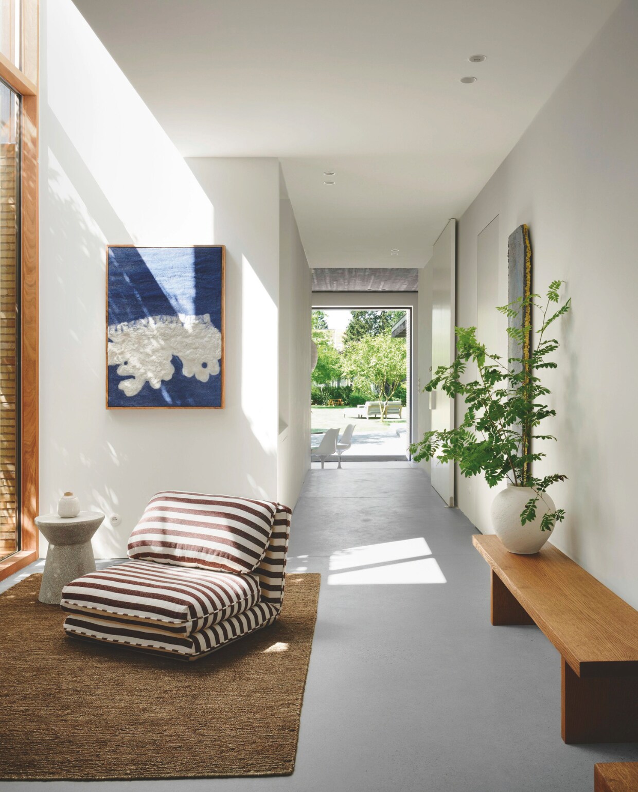 De grote houten raampartij geeft de hal extra warmte. Fauteuil Zara Home, tapijt Loook. stijlvol wonen | 2-2025 | fotografie Mr Frank | tekst Maya Toebat