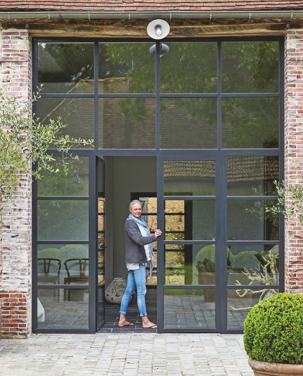 Waar eens de staldeur zat, staat Line nu bij de openslaande deuren. vtwonen landelijk 03-2025 | Productie House of Pictures | Brontekst Ingrid SkaansarStyling José Spaans | Fotografie Sarah Van Hove