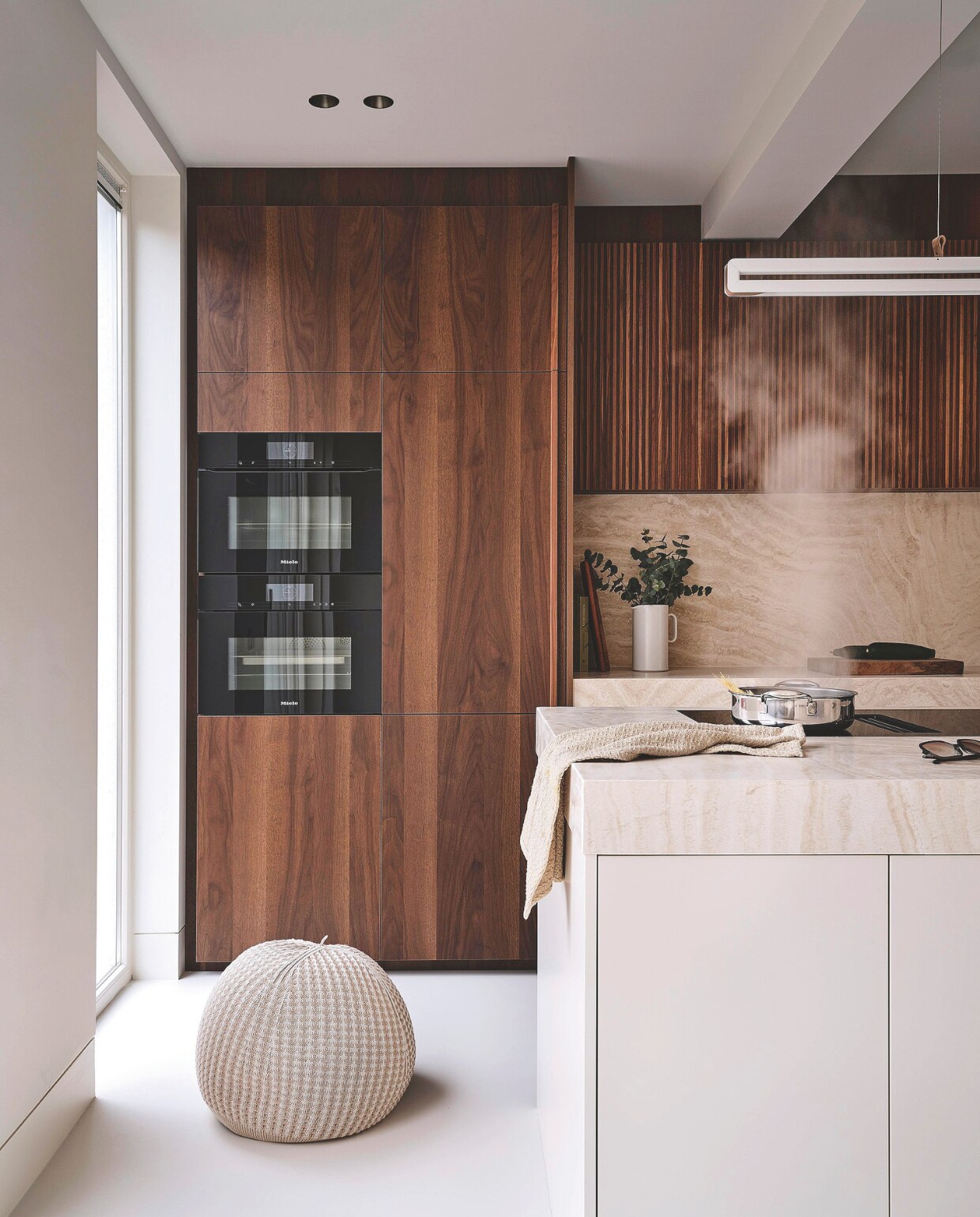 ‘Wij houden van koken en hebben vaak de kinderen en vrienden over de vloer. Daarom hebben we een wijnklimaatkast, twee ovens én twee koelkasten. Verder wilde ik een eiland dat onderdeel is van de keuken. Het heeft dezelfde kleur als de vloer, zodat het als het ware omhoog popt.’ Hanglamp Framed up-down van Jacco Maris. Poef Noort Interieur. vtwonen Stijlvol 4-2025 | Fotografie Space Content Studio | Tekst Eveline Stoel