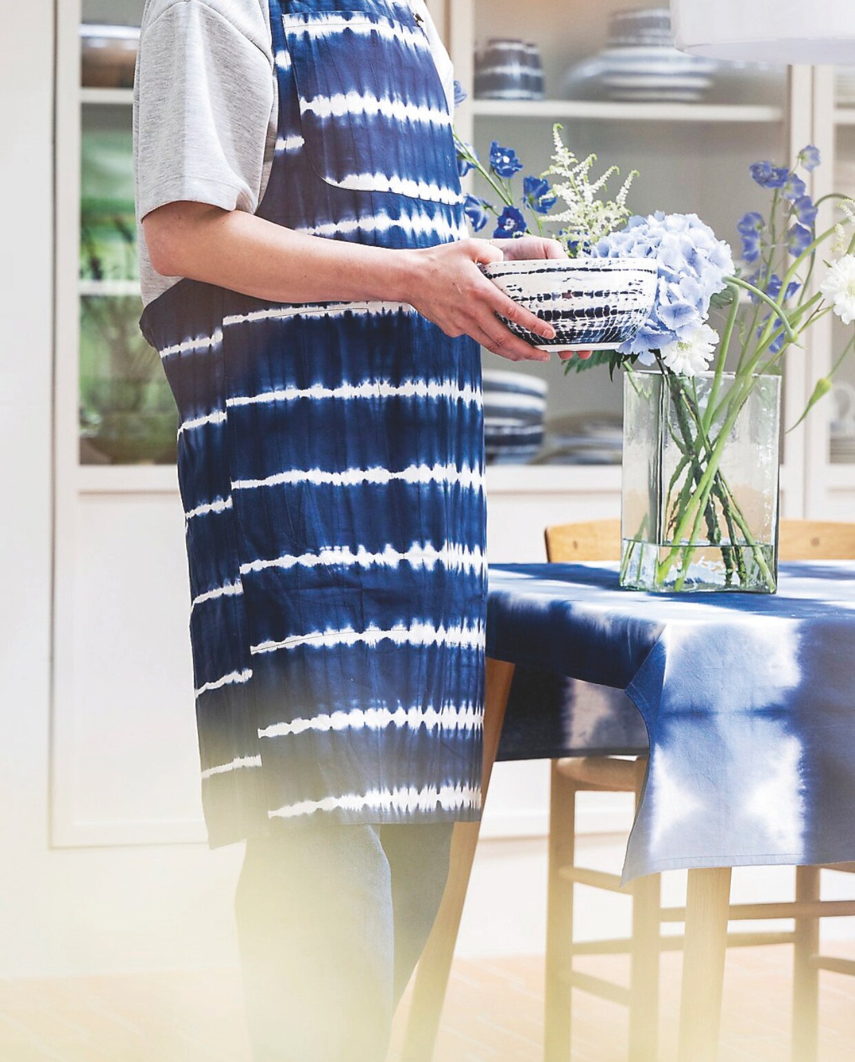 Katoenen schort Tie-Dye € 34,95, katoenen tafelkleed Tie-Dye, 250x150 cm € 59,95 en porseleinen saladekom Tie-Dye, 20,5 cm (Ø), set van 2 € 59,90. vtwonen 04-2025 | styling Kim van Rossenberg | fotografie Stan Koolen
