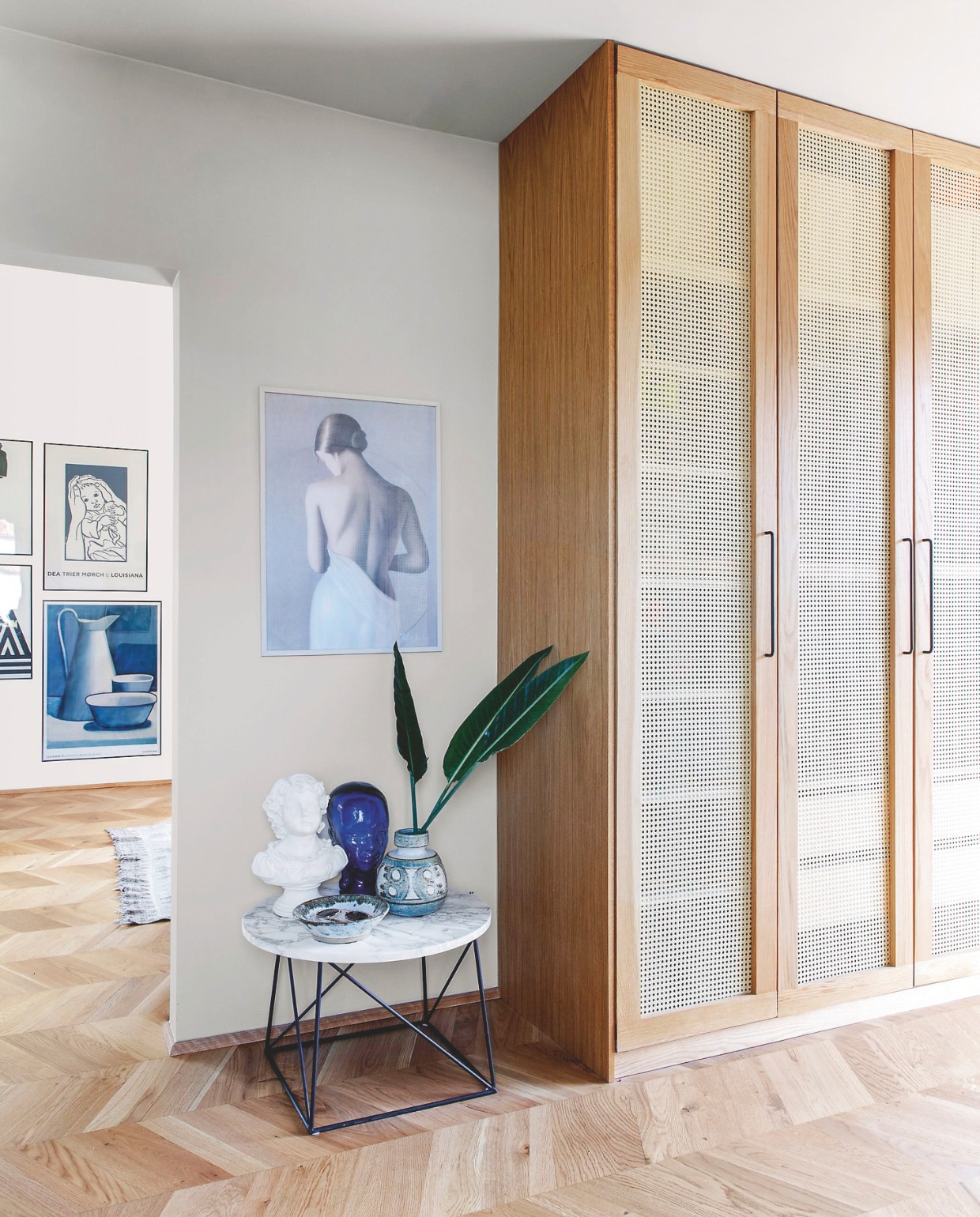 Kast Pax van Ikea, eikenhouten ombouw en deurframes met rotan op maat gemaakt. Marmeren tafel erfstuk. Poster van een straatartiest in Parijs. vtwonen 04-2025 | styling Rikke Graff Juel | fotografie Christina Kayser O