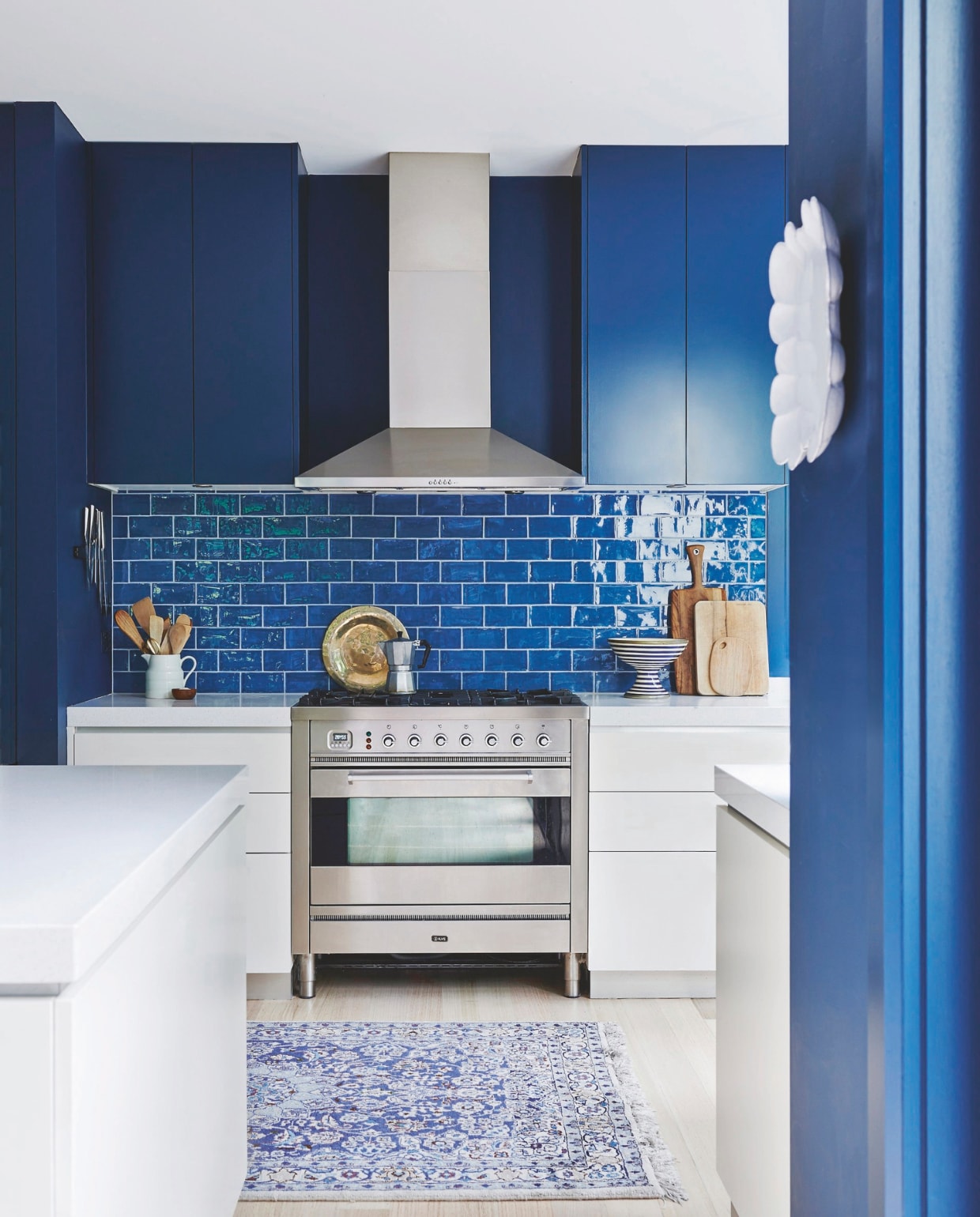 Muurkleur afgestemd op Hague Blue van Farrow &amp; Ball. Wandtegels Azul Zafiro via Signorino. Bord Astier de Villatte. Vintage vloerkleed Leonard Joel. Gestreepte kom Tom Dixon. Melkkan, lepels en fruitschaal vintage. vtwonen 04-2025 | styling Fiona Richardson | fotografie Lisa Cohen
