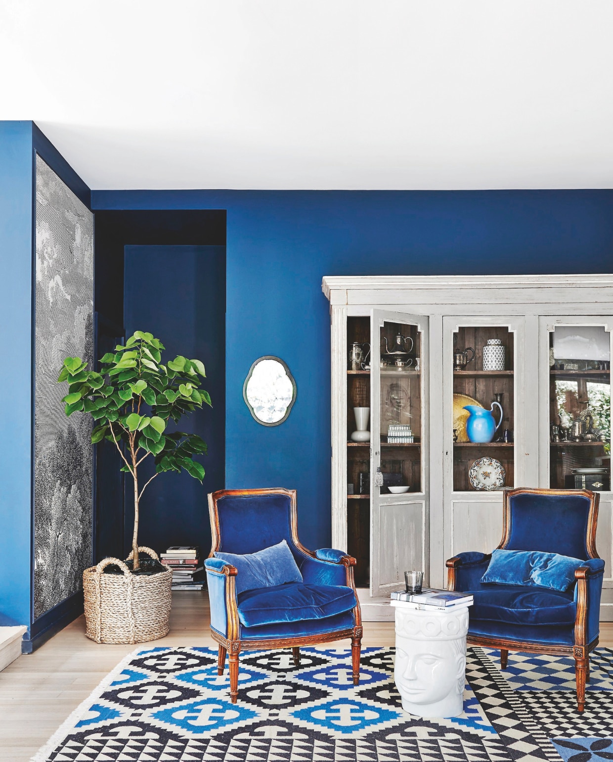 Muurkleur afgestemd op Hague Blue van Farrow &amp; Ball. Behang Arcadiavan Anthropologie. Kast The Bronte Tram. Vintage fauteuils bekleed met katoenfluweel van Maharam. Vloerkleed Kilim Palermo van Gan via Hub furniture. Spiegel Leonard Joel. Bijzettafel The king of Cambodia van Nyary Es. vtwonen 04-2025 | styling Fiona Richardson | fotografie Lisa Cohen