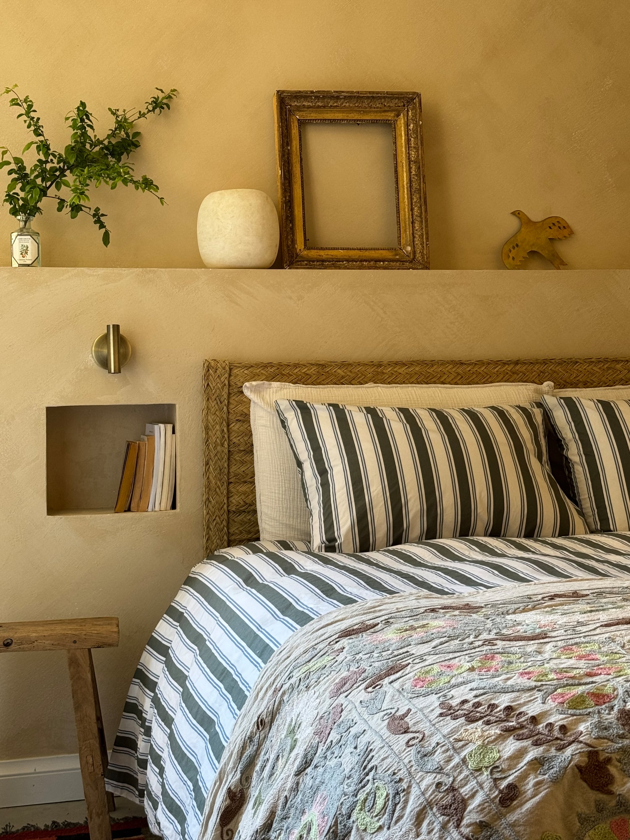 Bed en stoel Emma Sleep. Beddengoed Bonsoirs, vloerkleed Pompon Bazar. Leeslampjes Mantra, schilderij Tinystories, bankje vintage. Vloer, wand en plafond gepolijst beton. vtwonen 07-2025 | fotografie Manon Ferra