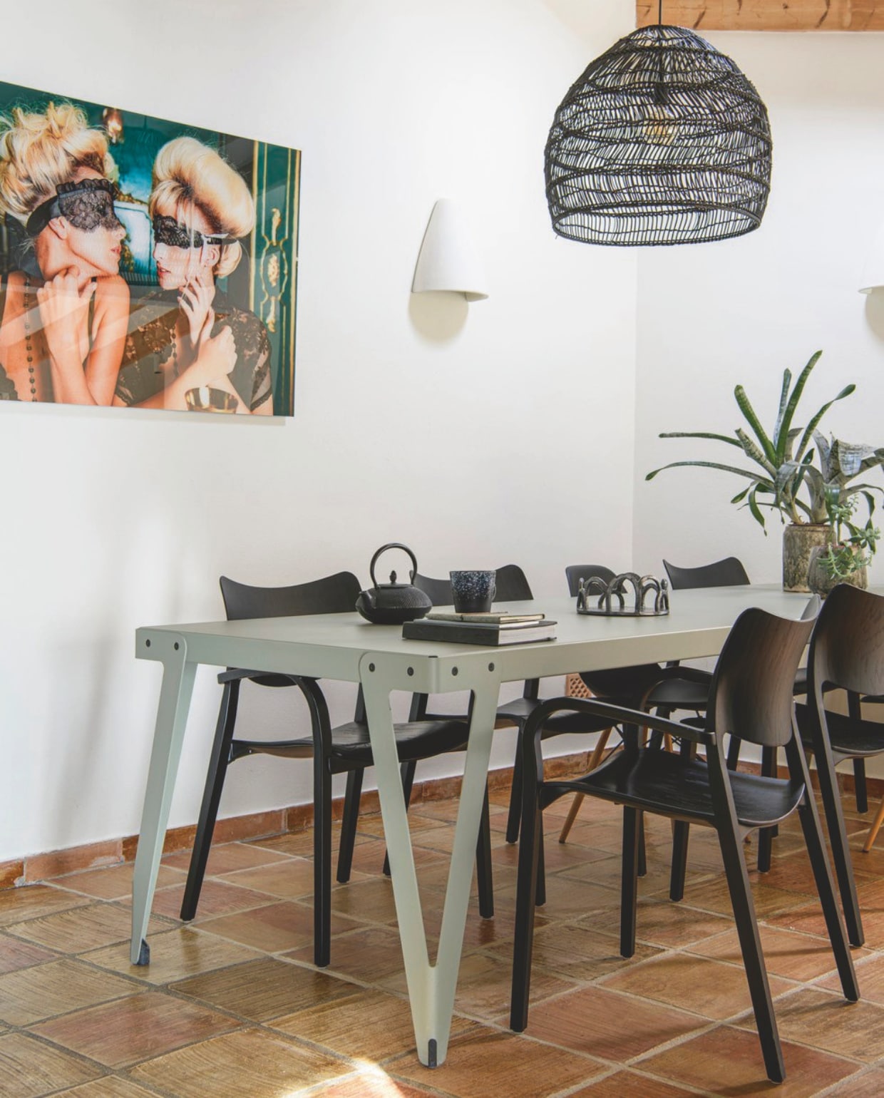 Tafel Lloyd van Functionals. Zwarte houten stoelen Stua. Zwarte kunststof stoelen Vitra. Lamp en theemok HKliving. Foto Jordi Gomez via Cobra Art. Fruitschaal zelfgemaakt. Gietijzeren theepot onbekend. Vloer originele vloer uit de finca. Wandlamp (teja) van lokaal keramiekbedrijf. vtwonen zomerboek 2025 | styling Inge van Lieshout | fotografie Louis Lemaire | tekst Merel van der Lande