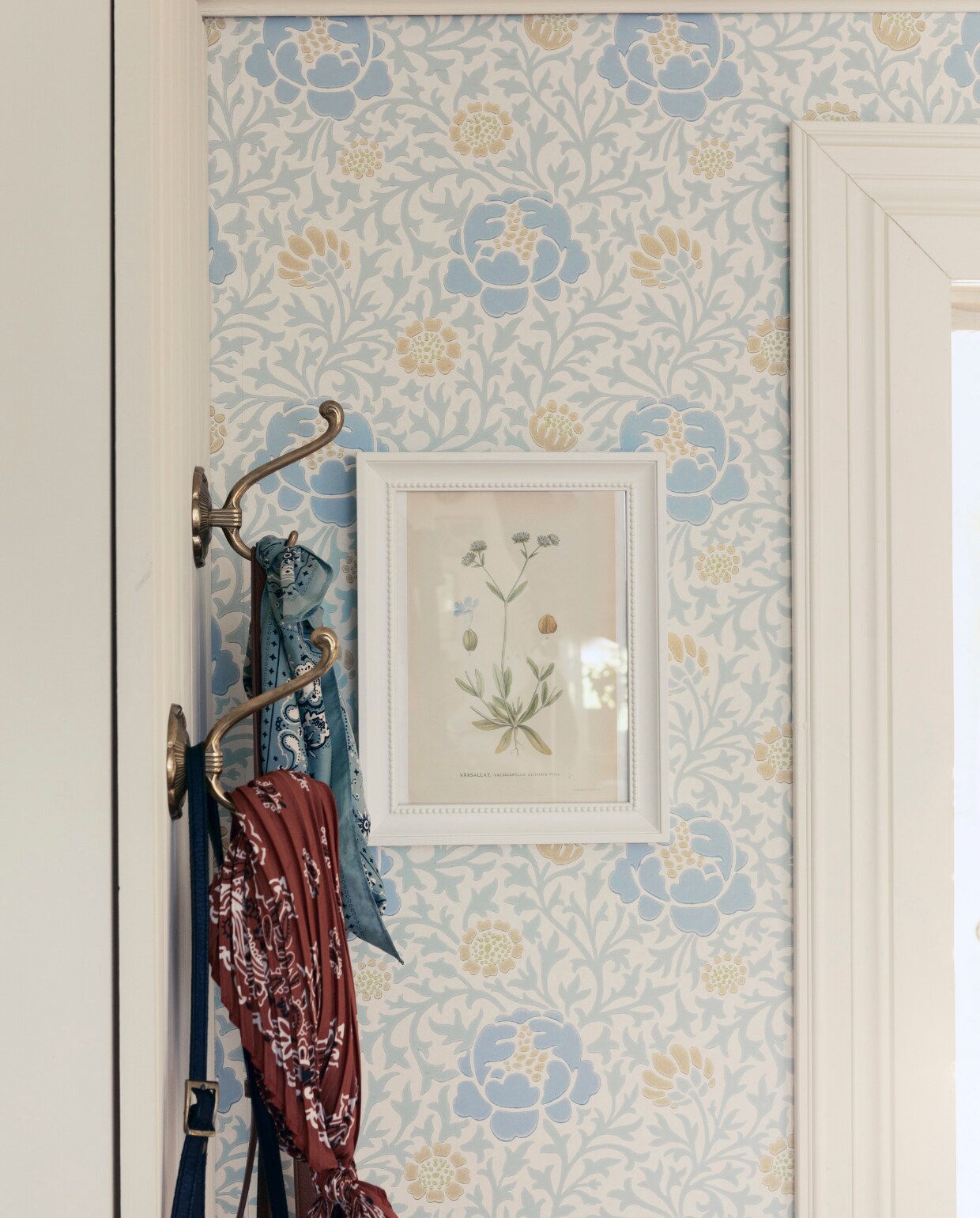 Prachtige tinten. Voor de entree koos Jenny het behang ‘Lansdowne Walk’ van Little Greene, omdat het zonnig, zacht en warm is een welkom voor zowel gasten als bewoners.De messing wandhaken zijn al jaren geleden op de rommelmarkt gevonden.De kleine prent in de lijst past perfect bij het kleurenpalet. vtwonen Landelijk 06-2025 | styling, fotografie & tekst Heikki Rautio | productie Studio Rautio