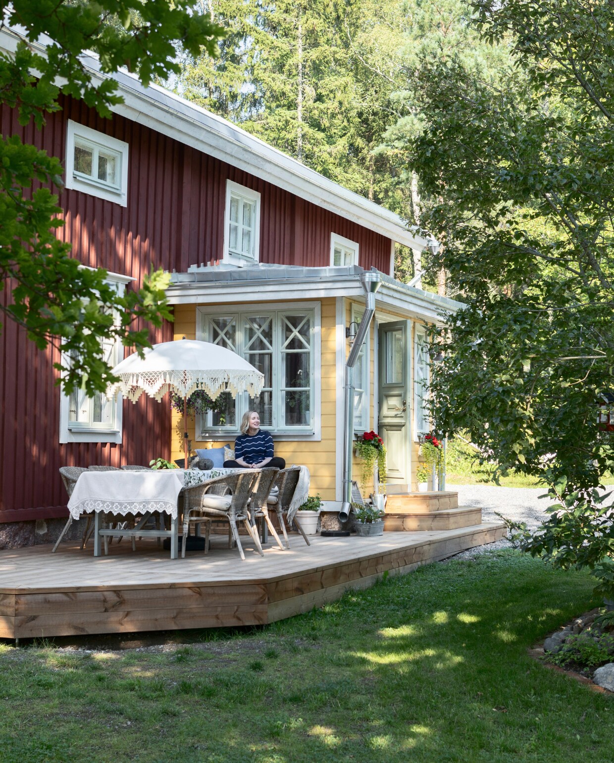 Voor het huis ligt een ruim terras, groot genoeg voor een grote eettafel.Jenny maakte een knus zitplekje naast de veranda, beschut tegen de wind.De kozijnen en raamframes zijn geschilderd met lijnolie-verf. vtwonen Landelijk 06-2025 | styling, fotografie & tekst Heikki Rautio | productie Studio Rautio
