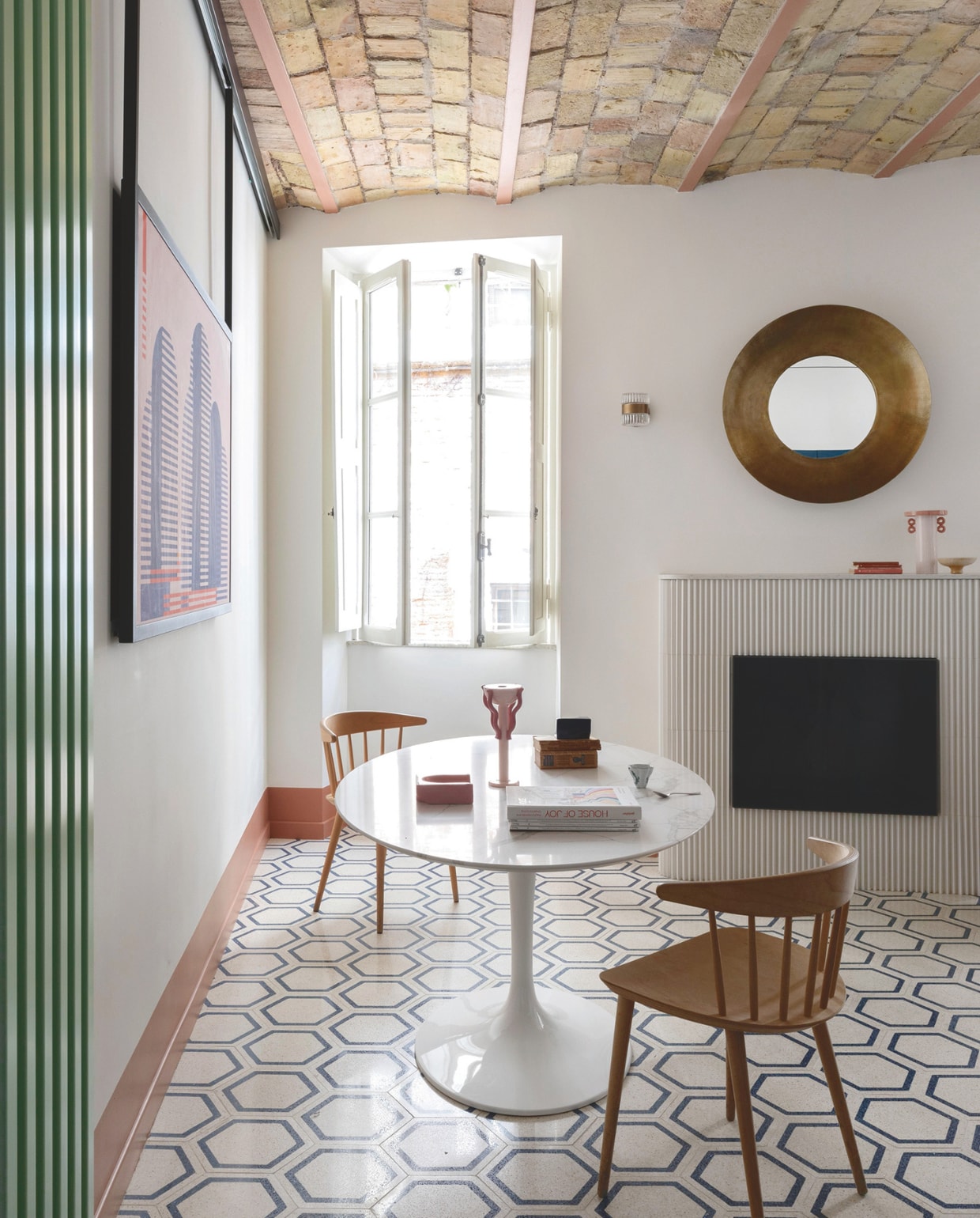 Vintage tafel uit de jaren 60. Stoelen Hay. Vaas en kaarsenhouder Arianna De Luca. Gekleurd keramiek van Zaven voor Vero International. Print Irena Pavlyshyn. Groene radiator Tubes. Tegelvloer Mosaic Factory. Wandlamp Soho Home. Stijlvol Wonen 04-2025 | styling Francesca Sironi | fotografie Monica Spezia | tekstbewerking Tanne Donjarcour Gielen | prouctie Living Inside | tekst Francesca Sironi