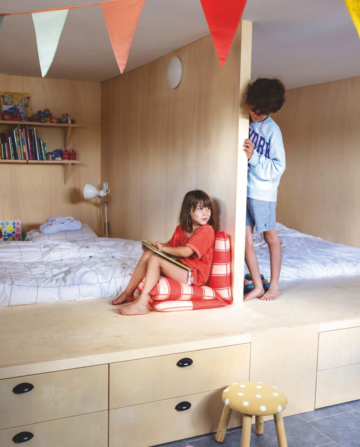 Bedstee op maat gemaakt door timmerman. Vlaggetjes Dille & Kamille. Rode kussens Zeeman. Beddengoed Wehkamp. Kruk Kwantum. vtwonen 05-2025 | styling Ilona Jongepier | fotografie Dana van Leeuwen