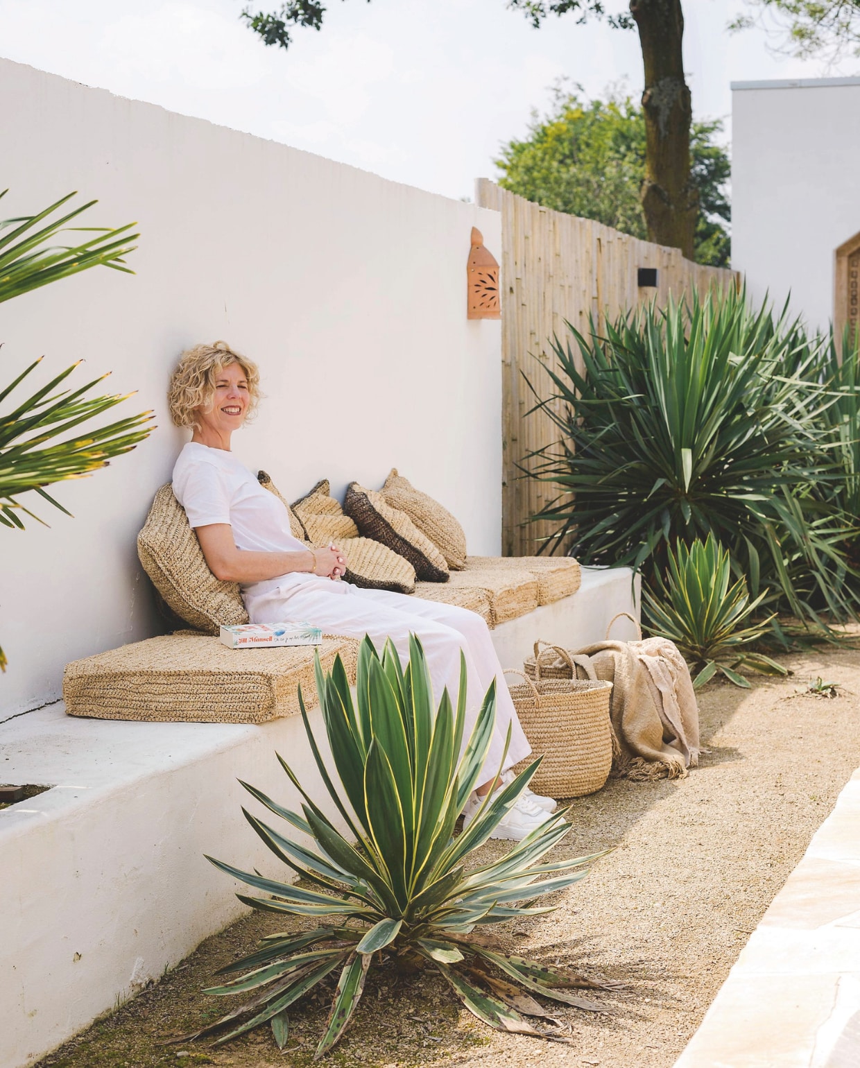 Linnen plaid, manden, sisal matraskussens, jute kussens en onbehandelde bamboedelen van 2x2 meter Coco homeliving. Terracotta wandlamp Tamegroute Shop. Zwarte lamp Light &amp; Living. Agaveplant Hornbach. De planten achter komen uit een voormalige horecagelegenheid. vtwonen special zomerboek 12-2025 | fotografie Corine Hoge Bavel-Jansen | tekst Caroline Westdijk