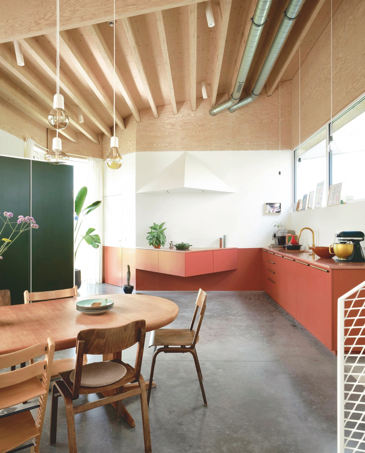 Vintage eettafel via Nome Furniture, vintage stoelen overgenomen van een cultureel centrum. Lampen Zangra. Keuken en kast van groen betonplex Dries Otten. Inductiepitten Novy. Peper- en zoutmolen Hay. Gietijzeren stoofpan en olijfoliekan Dille &amp; Kamille. Mixer KitchenAid. Stalen trap door Meca-Welding. vtwonen 05-2025 | fotografie Mr. Frank | tekstbewerking Britte Kramer