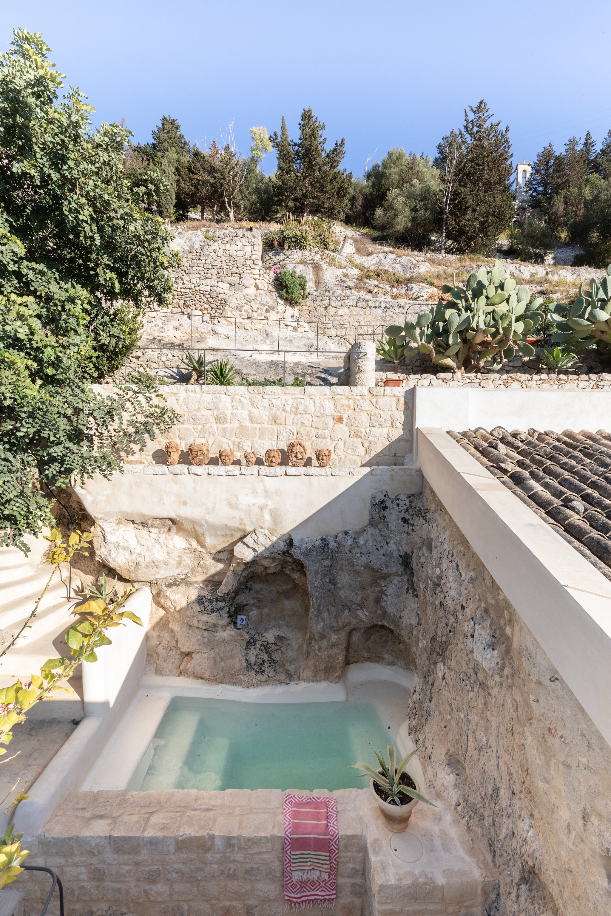 Het kleine, uit rots gehouwen zwembad. Het stuukwerk is nonchalant en afgerond, als zacht contrast met de ruwe steen. vtwonen 08-2025 | productie Living Inside | fotografie Monica Spezia