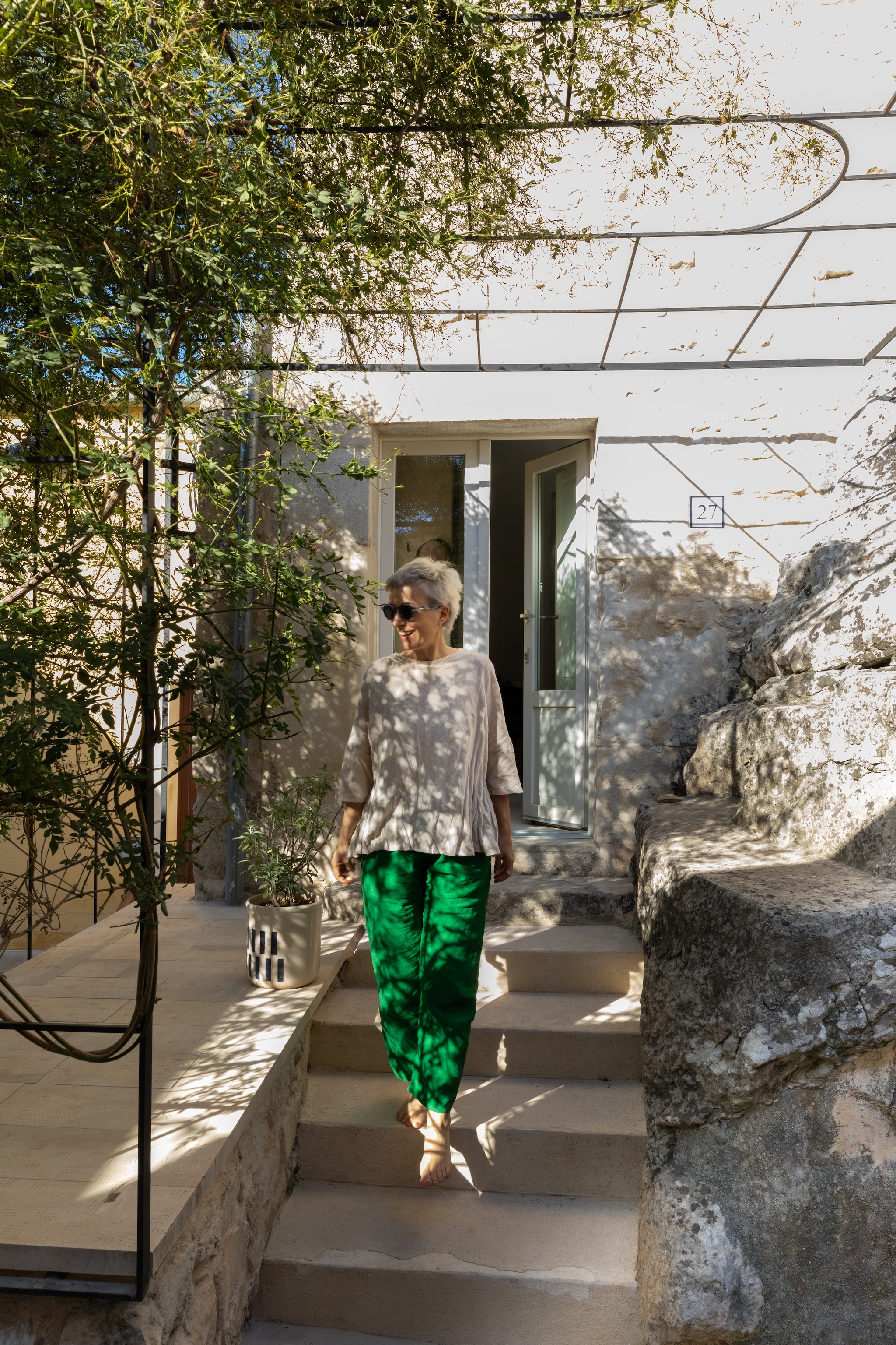 Een lokaal gesmede pergola naar eigen ontwerp biedt schaduw bij een ingang van de grotwoning. vtwonen 08-2025 | productie Living Inside | fotografie Monica Spezia