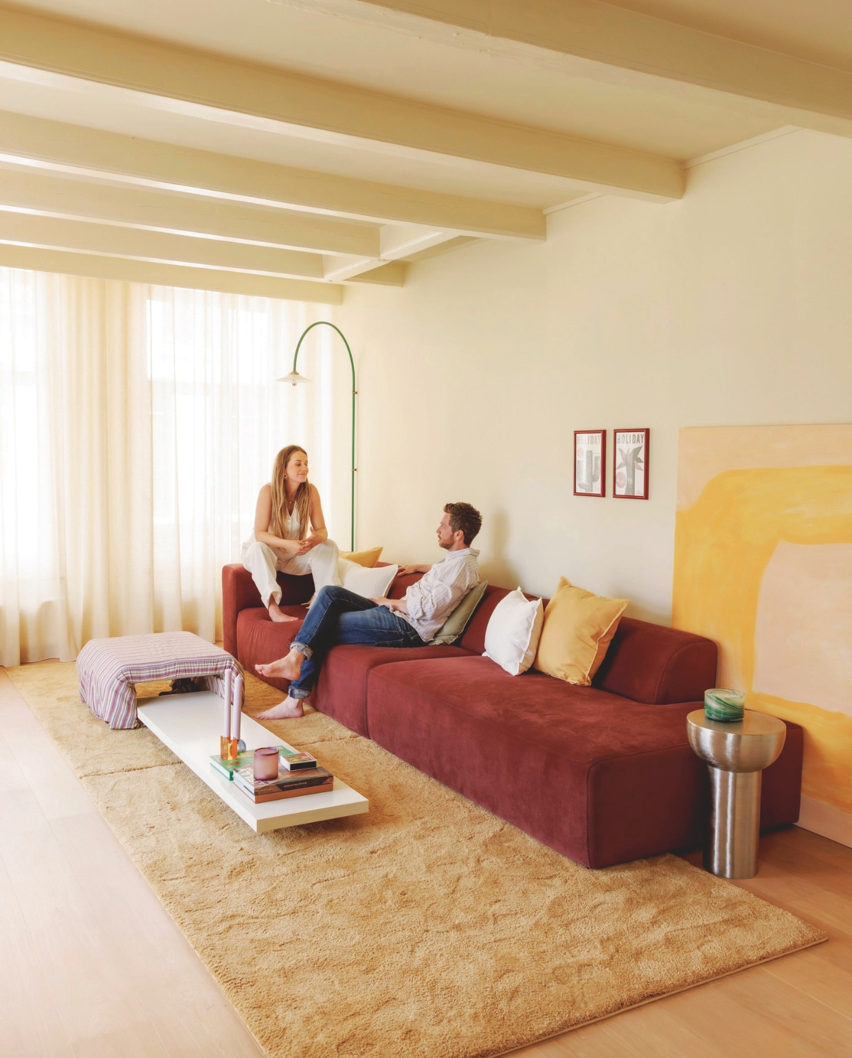 Muur en plafond in Asian Sunrise van Lab Paint. Gordijnen Nuzzle in Lemon Meringue van Vadain. Bank X6 van 4X6 Sofa in Wine Red. Poef en salontafel zelfgemaakt. Wandlamp Muller Van Severen voor Valerie Objects via Mud in May. Linnen kussens H&amp;M Home. Twee dezelfde vloerkleden tegen elkaar van Karwei. Waxinelichthouder HKliving. Kandelaars Fest. vtwonen 06-2025 | styling Kelly van Gendt | fotografie Emma Peijnenburg