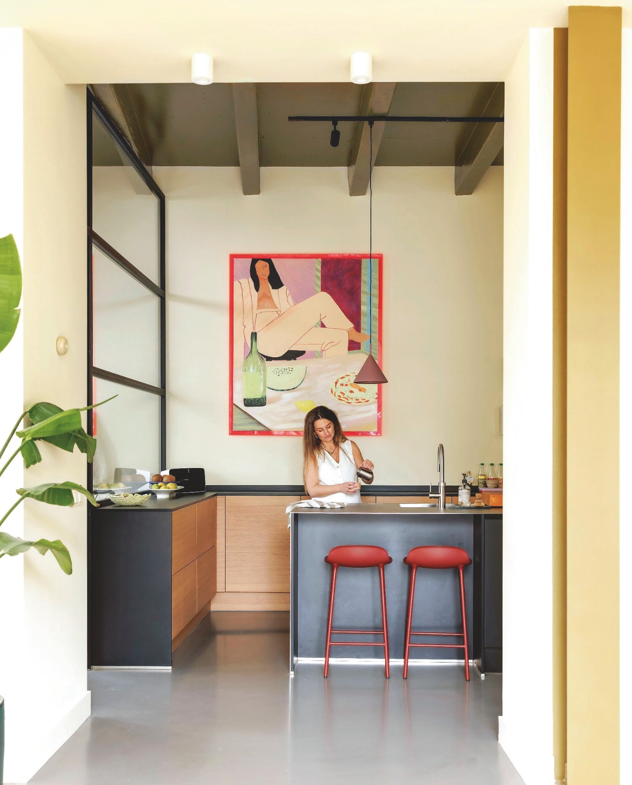 Muurkleur Asian Sunrise van Lab Paint. Plafondkleur High Gloss Lak in Fresh Olive van Pure & Original. Pilaar geverfd in Hunter van Lab Paint. Maatwerk keuken, blad van koudgewalst staal, houtfineer fronten. Kunstwerk Get Your Groove van HKliving. Barkrukken Normann Copenhagen. Schaal Maze van Stijn van Aardenne. vtwonen 06-2025 | styling Kelly van Gendt | fotografie Emma Peijnenburg