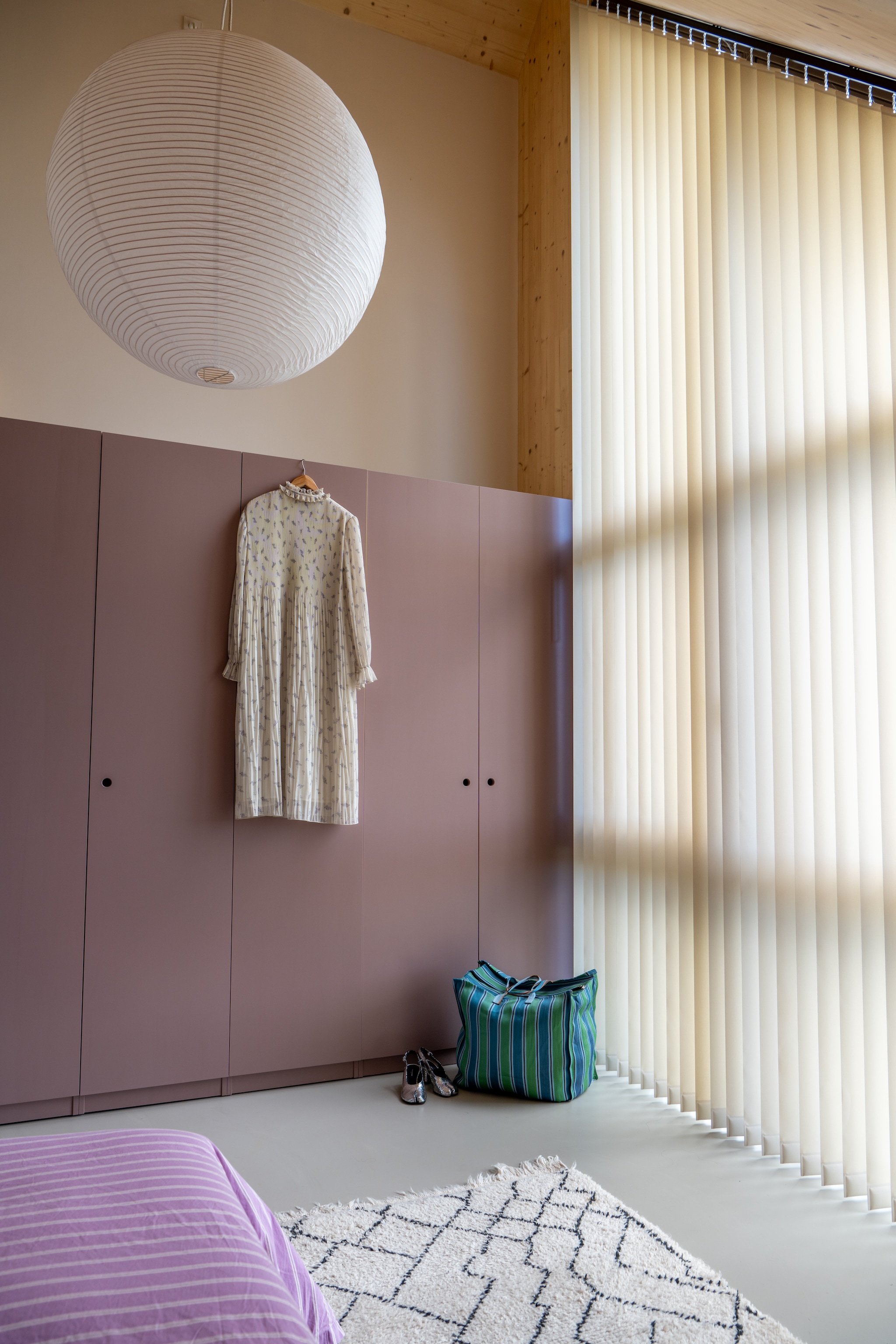 Kast van Standaard Maatwerk in Sulking Room Pink van Farrow & Ball. Lamp Hay, jurk Ganni, schoenen Tabi van Maison Margiela. Lamellen Luxaflex. Muurkleur Dimity van Farrow & Ball. Tas Westerstraat-markt in Amsterdam. vtwonen 09-2025 | styling Jasmijn Stegeman | fotografie Anke Leunissen