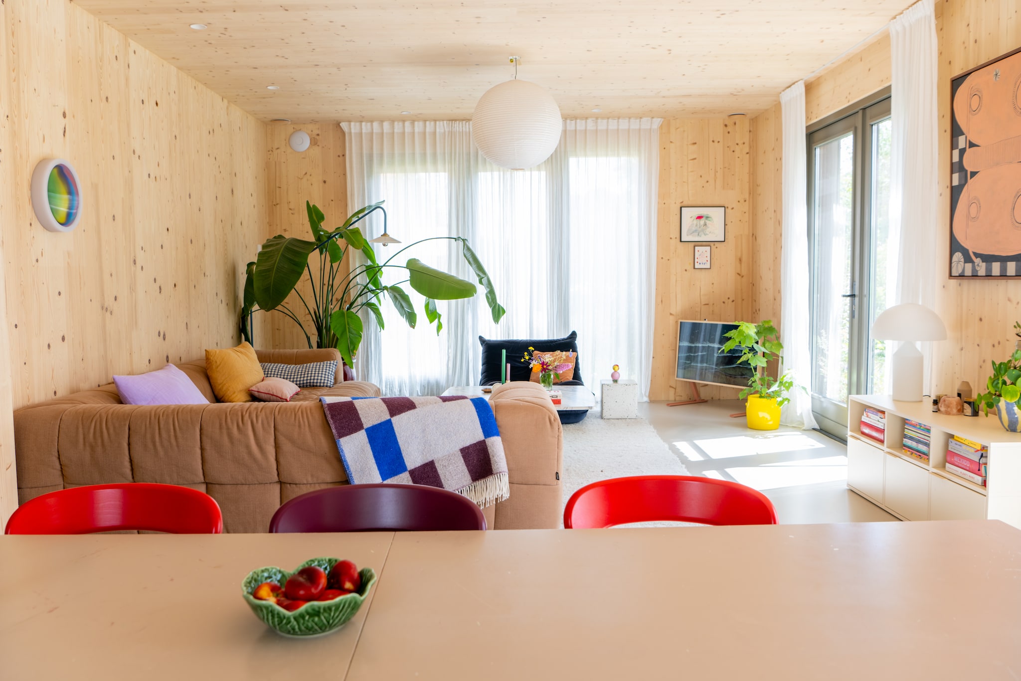 Bank Arflex, roze kussen HKliving, geruit kussen Pantoufle Design. Salontafel Marktplaats, kaarsenstandaard Hay, kaarsen Hema. Blauwe wandlamp Muller Van Severen, plantenpot geërfd. Fauteuil Togo van Ligne Roset. vtwonen 09-2025 | styling Jasmijn Stegeman | fotografie Anke Leunissen