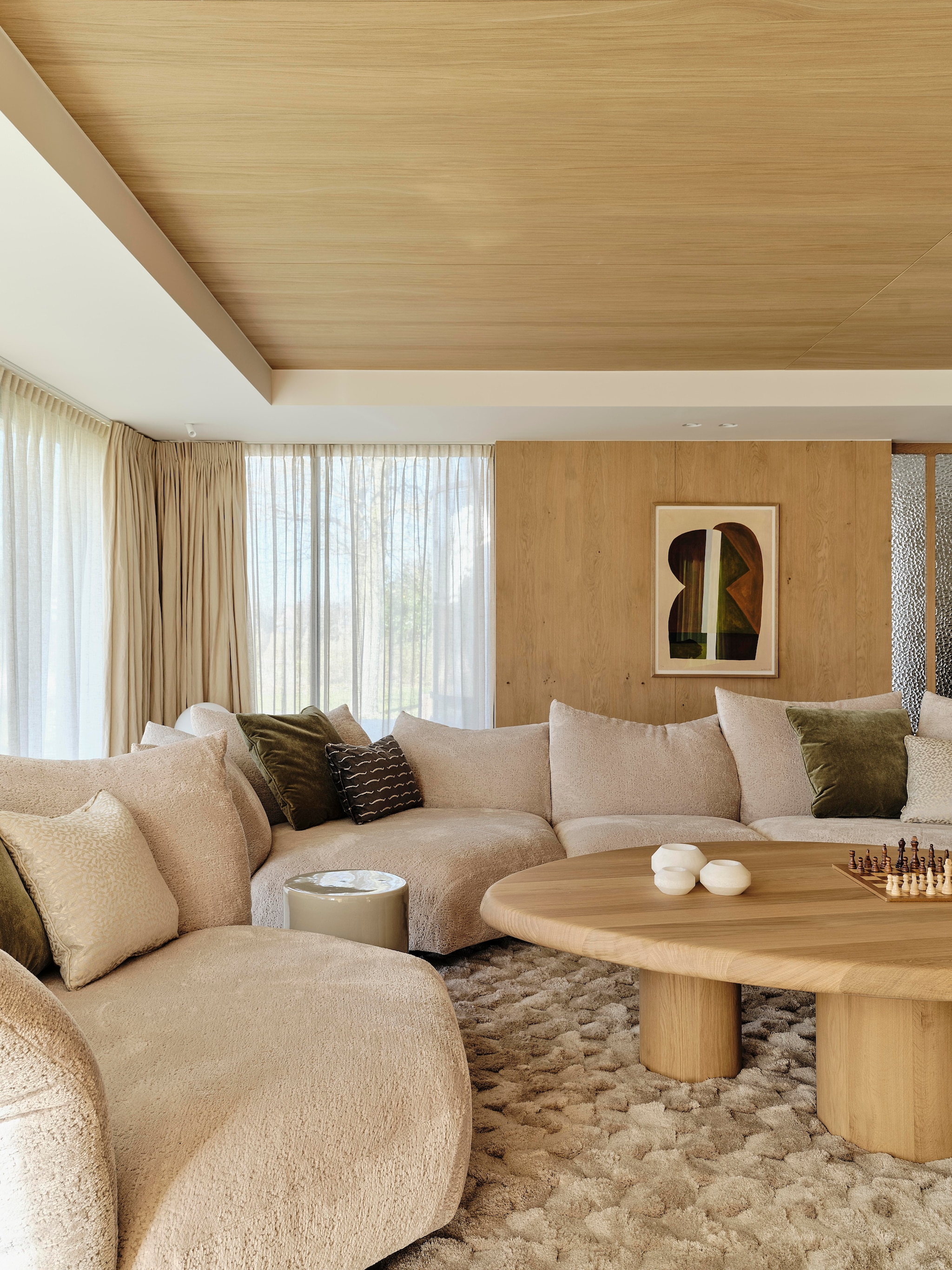 Modulaire bank Edra. Kussens gemaakt door Stoffeershop en bekleed met stof van Dedar en Zimmer + Rohde. Kleed Ferreira de Sá. Tafel Behout. Vazen Serax. Items planken links Maravillas, items planken rechts Roomer Art, Serax, HKliving. Tafellamp Oluce Atollo. Schouw Dover wit marmer. Zeegras behang Kudzu van Arte. stijlvol wonen 8-2025 | fotografie Space Content Studio