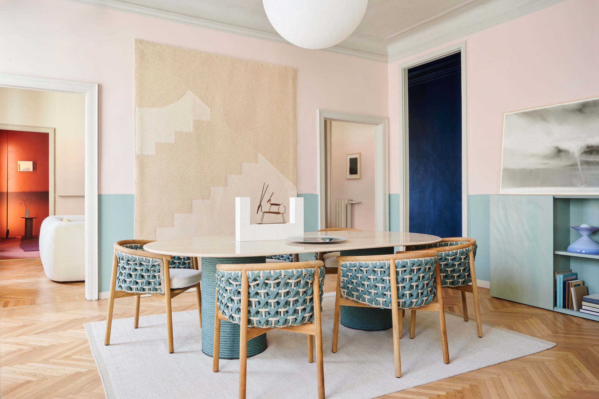 Tafel en stoelen Patio van Ethimo. Houten op maat gemaakte kast Desdemona Lunardelli Venezia. Wandkleed Cime van Saba. Lamp Moon van Davide Groppi. Verf blauw N1.06.61 daarboven D8.05.78 plafond en kozijnen F4.04.73 van Sikkens. Vloerkleed Everyday Sky van Cc-tapis. Kunstwerk rechts: Tornado van Francesco Pedrini. Stijlvol Wonen 8-2025 | fotografie Valentina Sommariva, Irene Gaggia | productie Zanellato/Bortotto