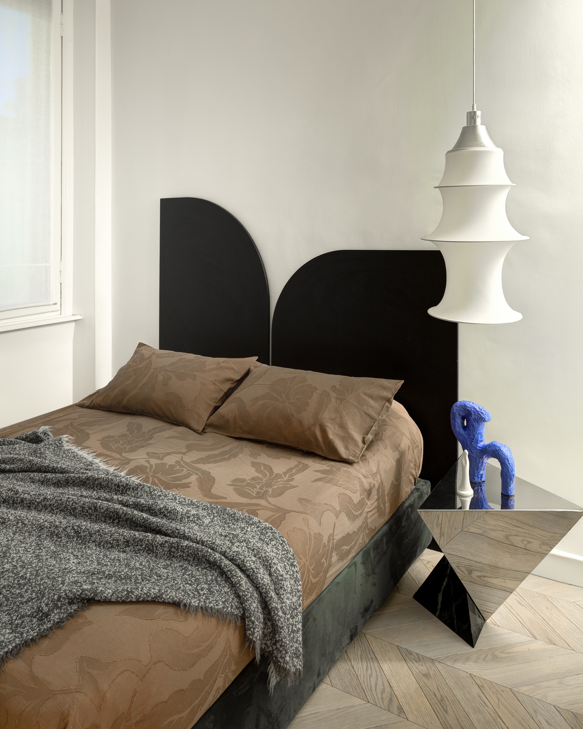 Het hoofdeinde van het bed en de bijzettafel zijn ontworpen door  Rudy Faissal. Hanglamp Falkland  van Danese.  Stijlvol Wonen 6-2025 I Productie Living Inside | Styling Giulia Taglialatela I Fotografie Mattia Iotti