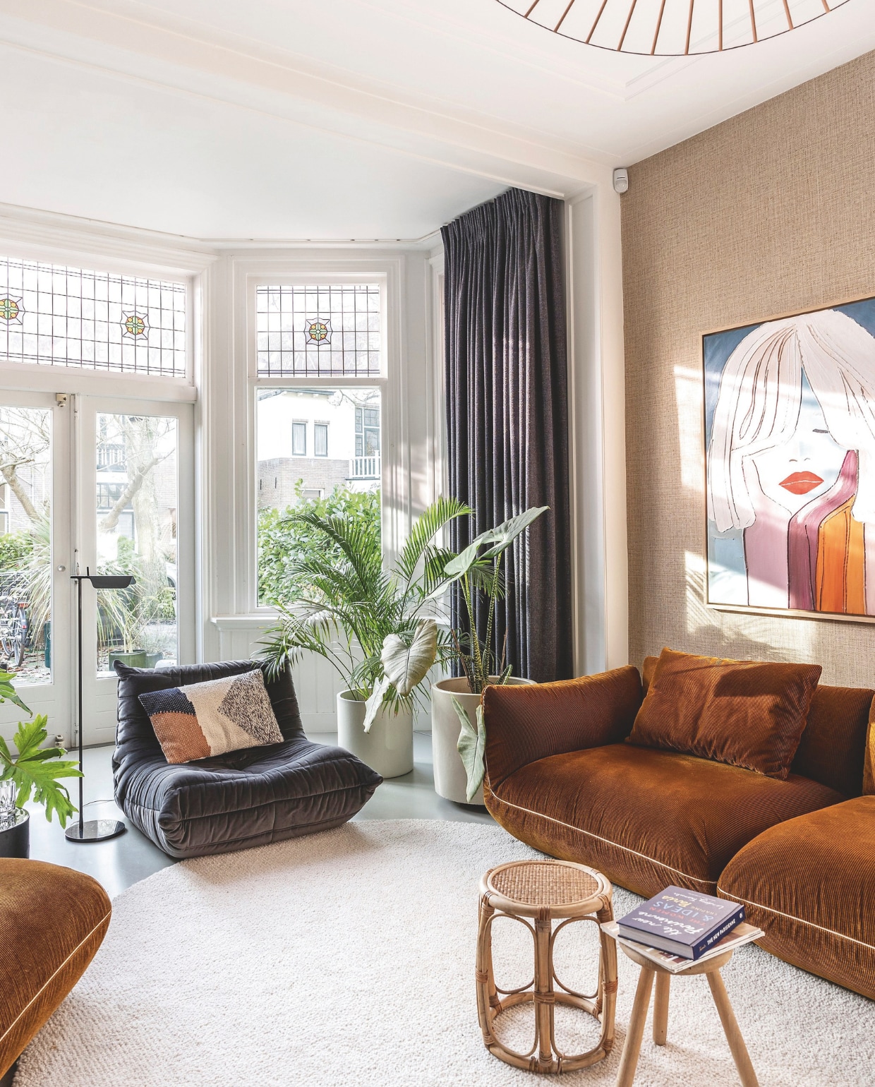 Camelkleurige bank en fauteuil Cor Design, fauteuil Ligne Roset, vloerkleed zelf ontworpen Jabo. Kussen HKliving, leeslamp Flos. Schilderij Casper Faassen. Epoxy gietvloer. Behang Arte. Kleur op de muur signaalwit van Karwei. vtwonen 7-2025 | fotografie Margriet Hoekstra | styling Room Rebelle