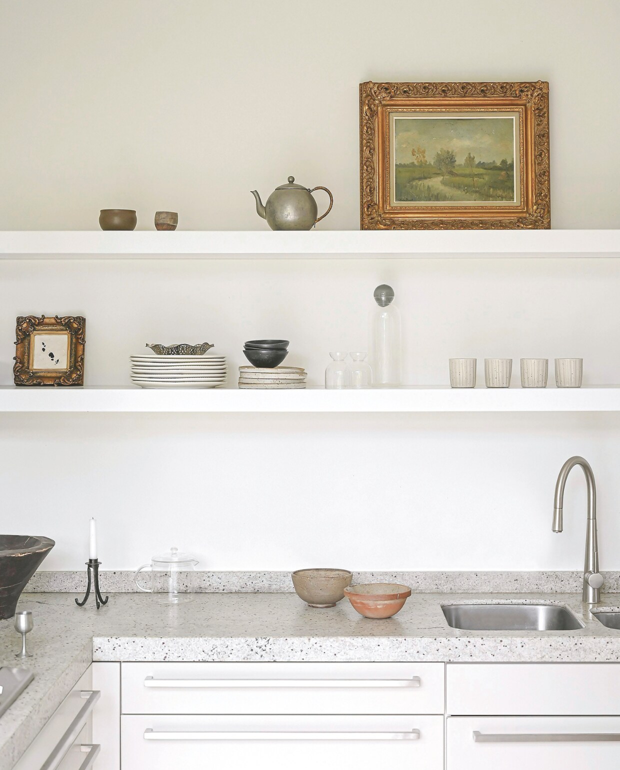 Werkblad van travertin. Kraan Moen. Handgemaakte theekoppen Atelier De Vonder. Keukenkasten SieMatic. Schilderij gemaakt door Kate, landschapschilderij antiek. Verder is bijna alles tweedehands. Stijlvol Wonen 06-2025 | fotografie Michiel Bosman