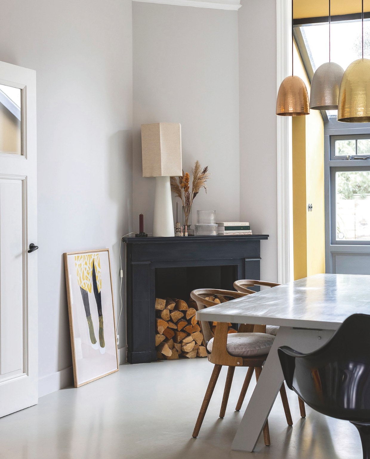 Tafel zelf geverfd Piet Hein Eek. Gerookt walnoten stoelen &Tradition, zwarte stoel Saarinen. Metalen lampen Original Btc, witte lamp HKliving. Kleur schouw Off-black van Farrow & Ball. Kleur op de muur zelf gemengd. vtwonen 7-2025 | fotografie Margriet Hoekstra | styling Room Rebelle